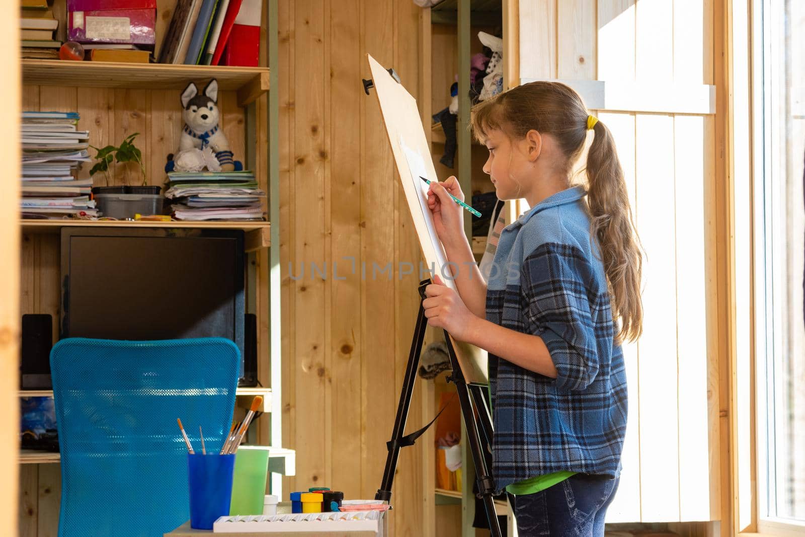 A ten-year-old girl draws on an easel at home