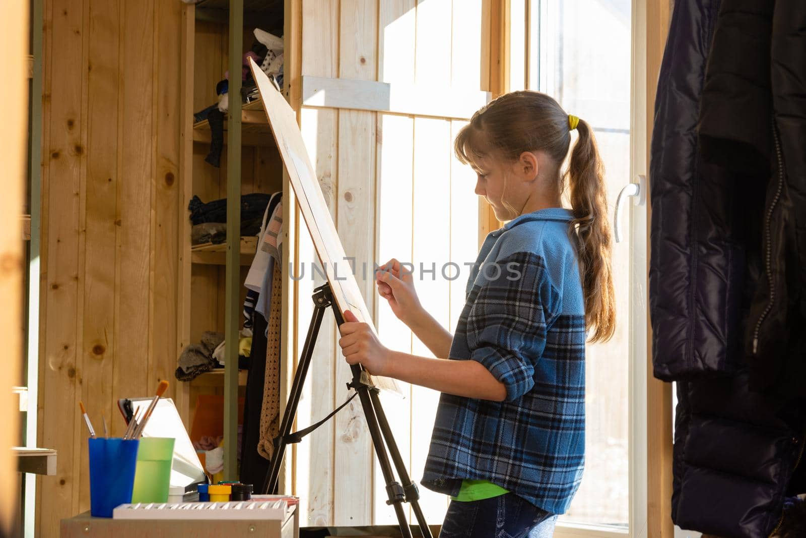 A ten-year-old girl makes a sketch on an easel, removes unnecessary details with a washing eraser