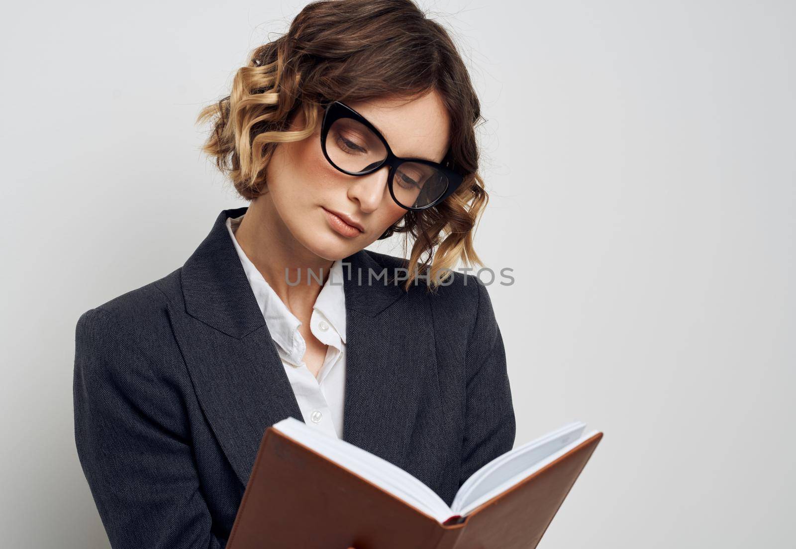 Business woman with book in glasses hands on face of classic suit by SHOTPRIME