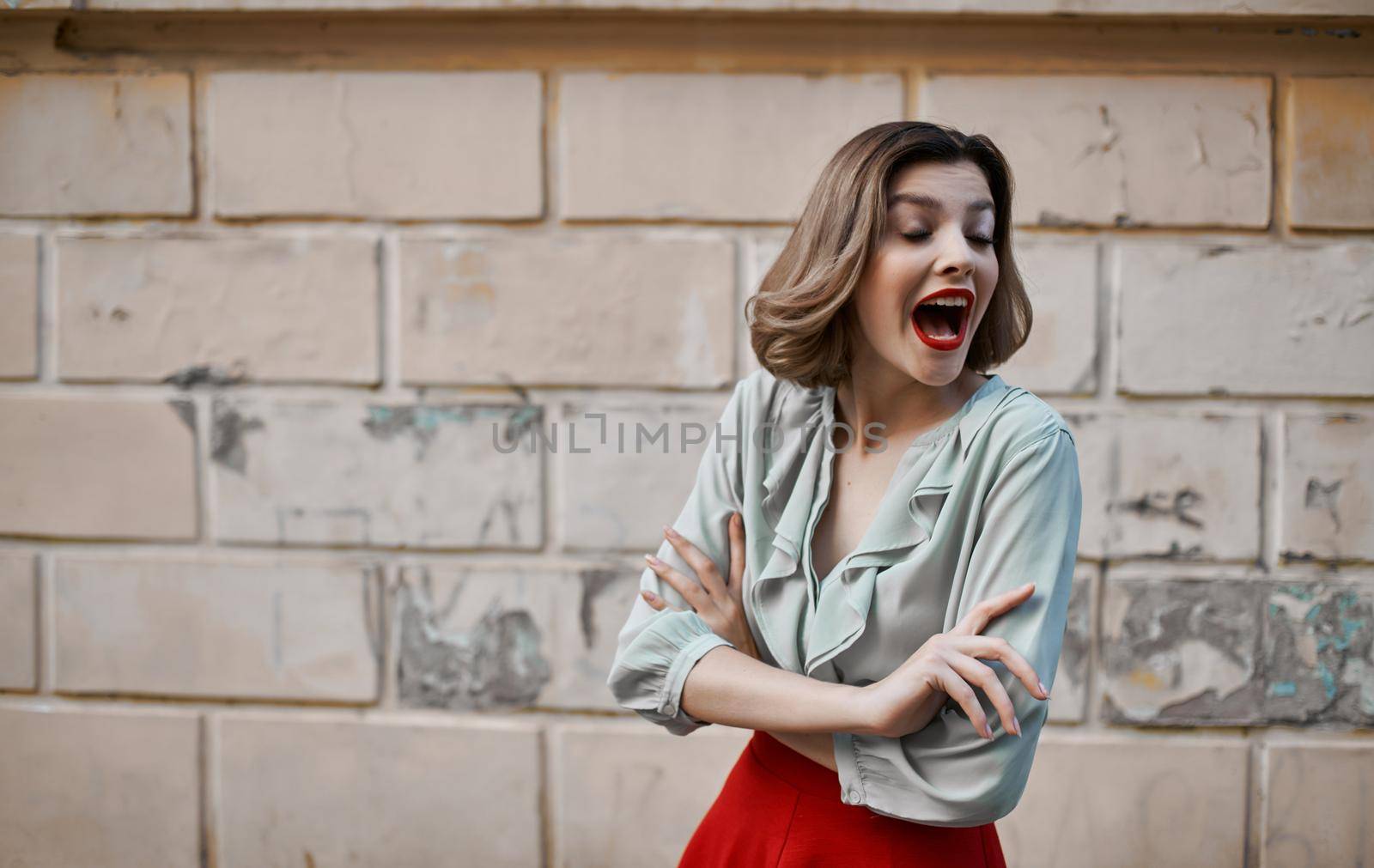 happy blonde girl with bright makeup near building gesturing with hands fashionable clothes style. High quality photo