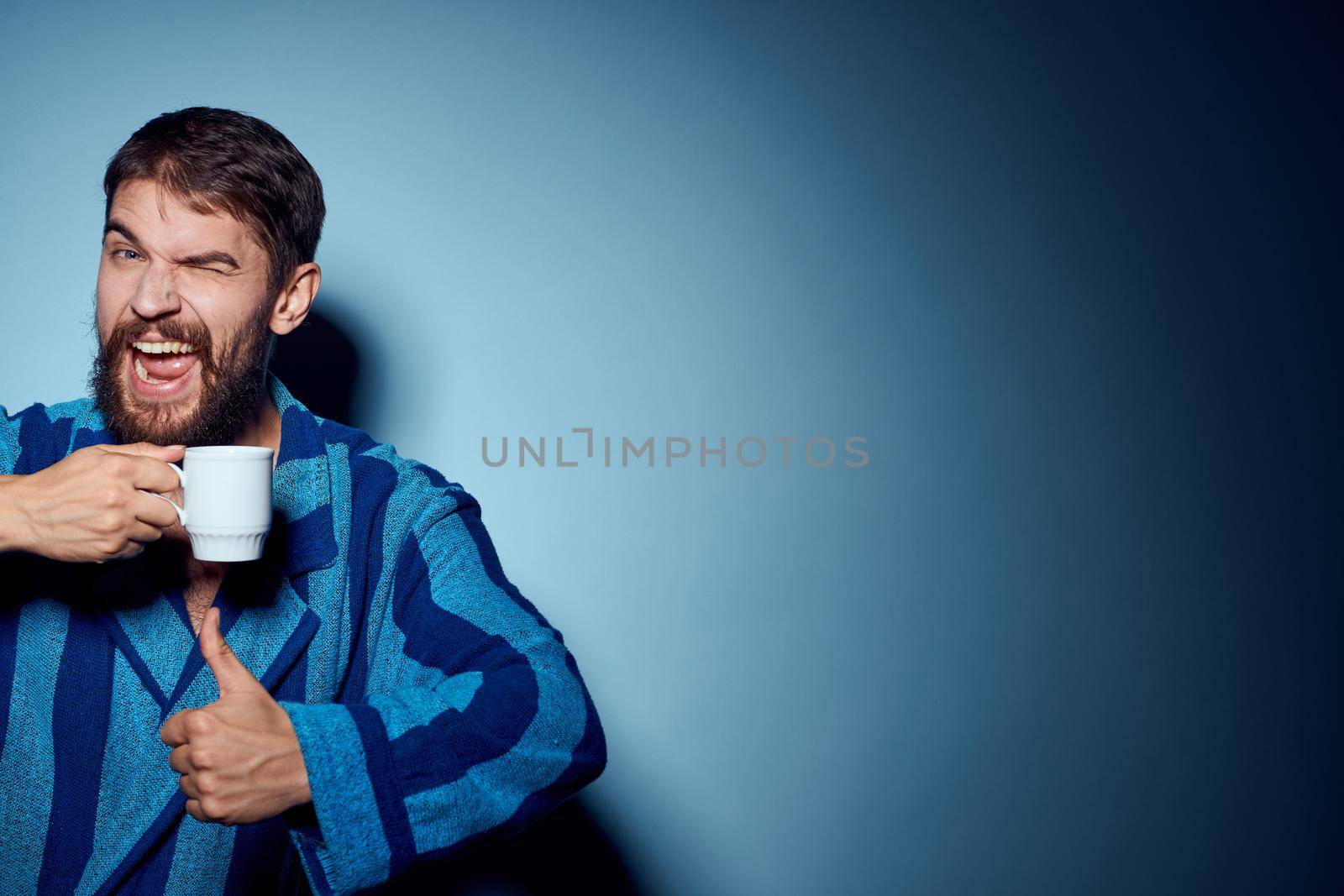 emotional man in pajamas morning lifestyle drink blue background. High quality photo