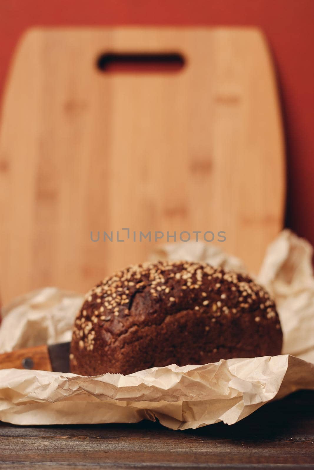 rye bread on a wooden table paper packaging sharp knife red background board by SHOTPRIME