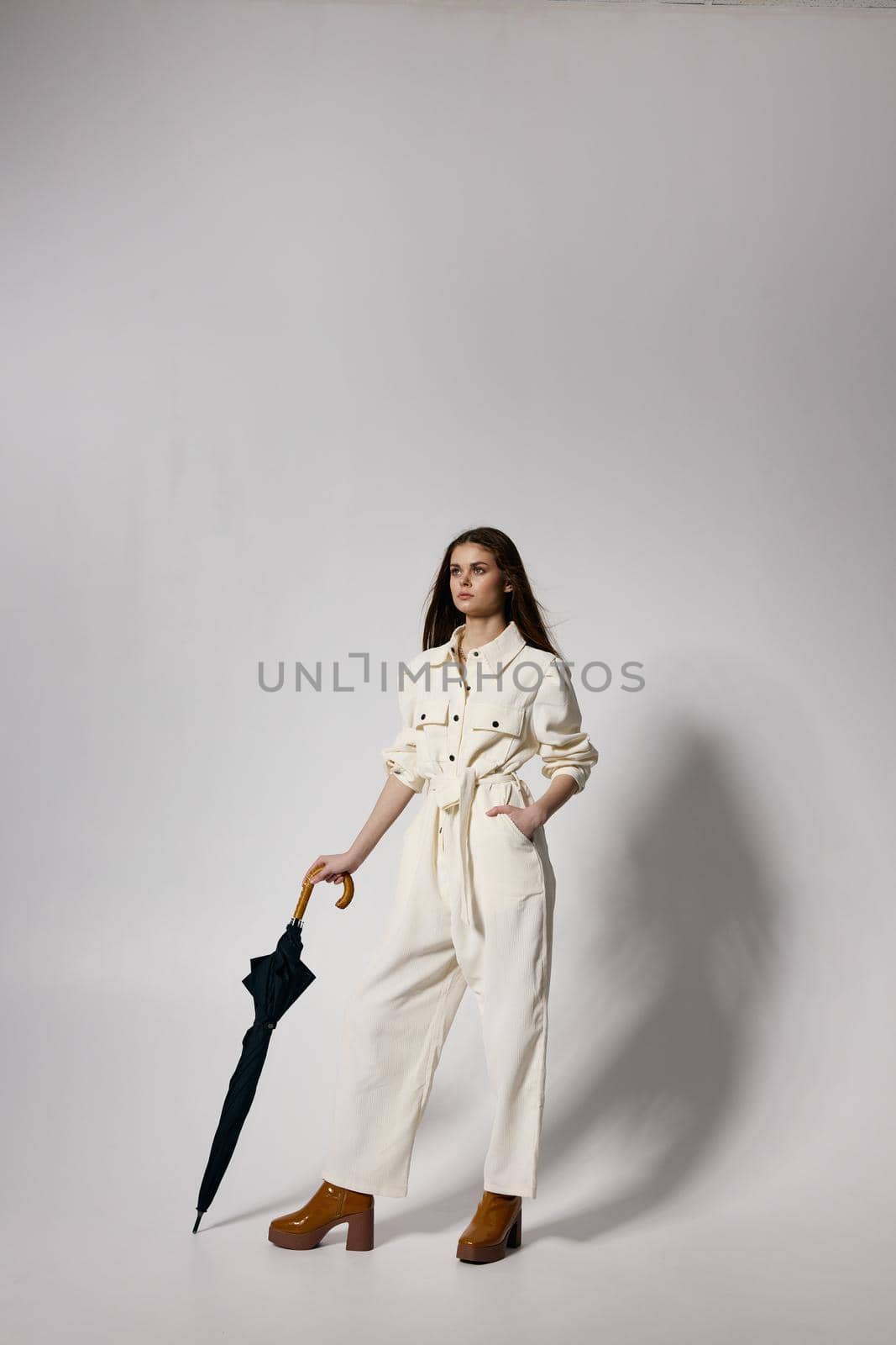 pretty woman in white suit holds hand in pocket umbrella in hands modern style. High quality photo
