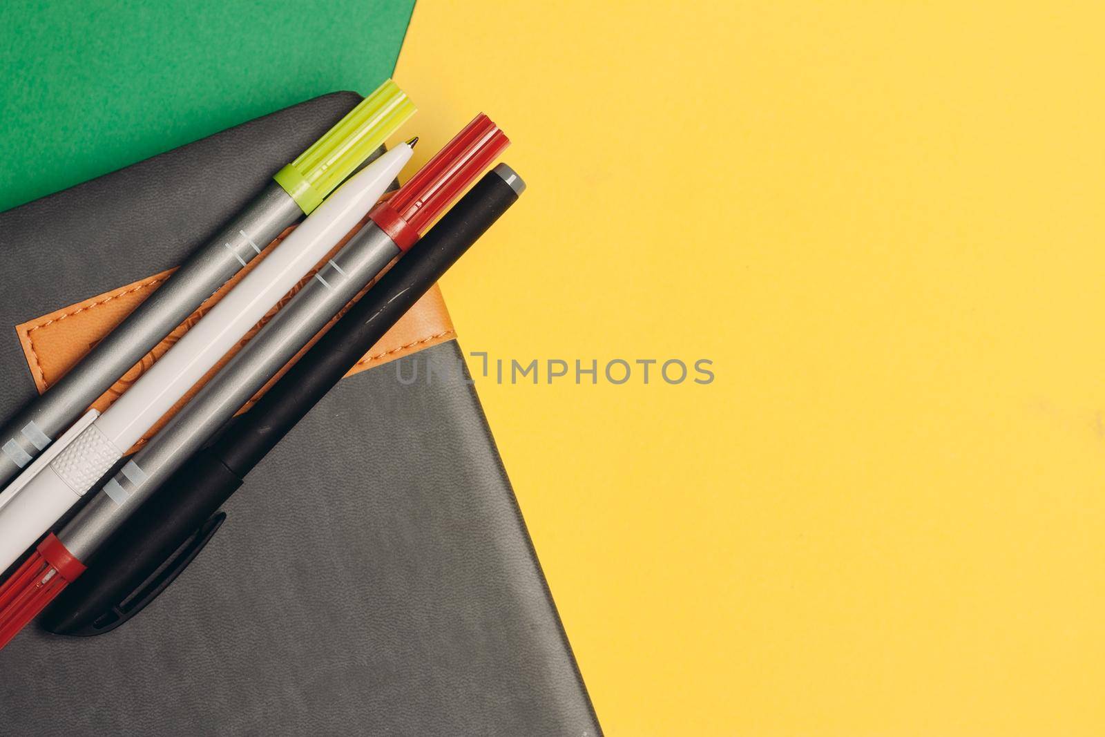 notepad markers pens office supplies and yellow green background. High quality photo