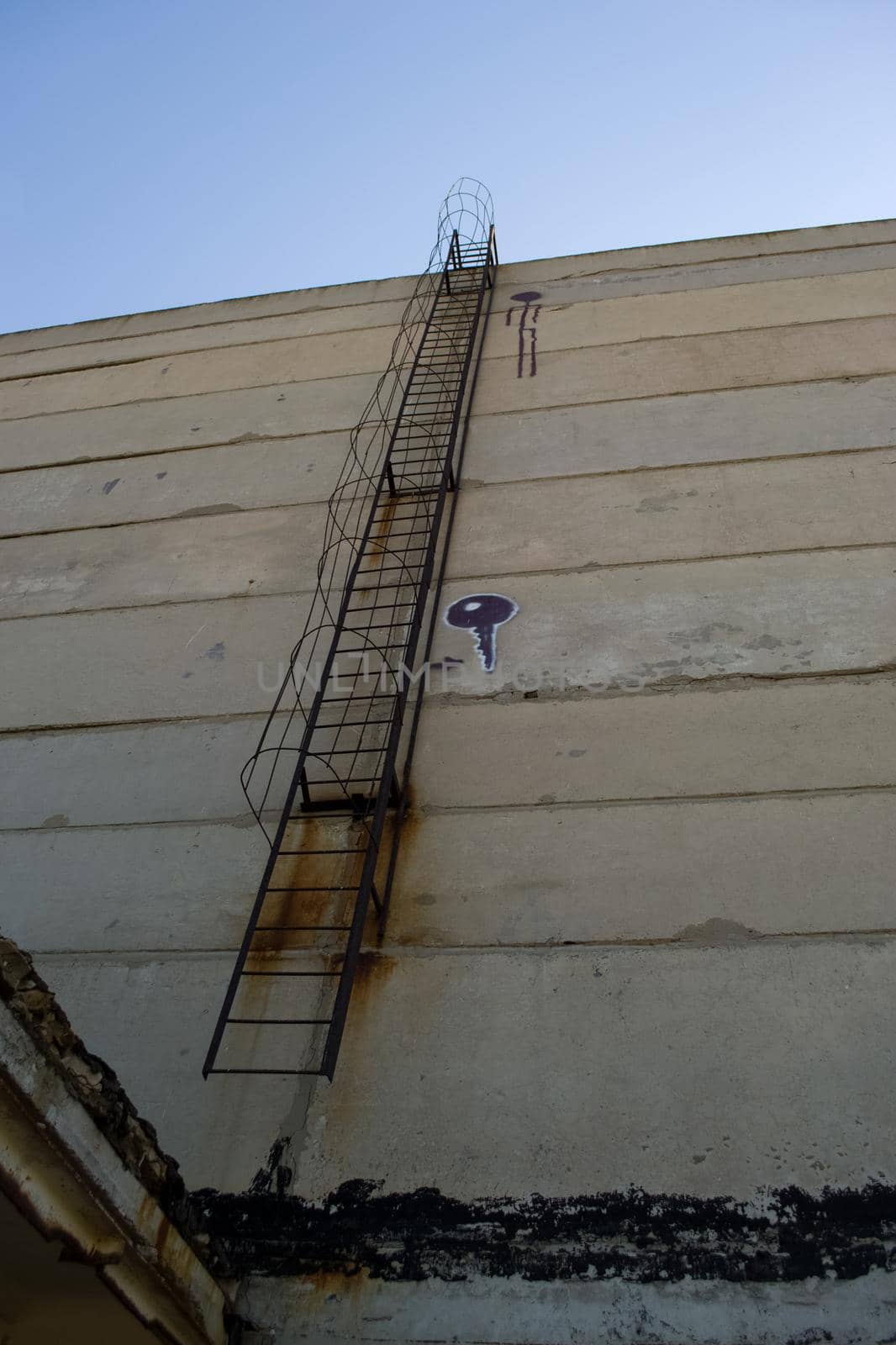 An old rusty staircase to the roof of the building. Abandoned industrial object.