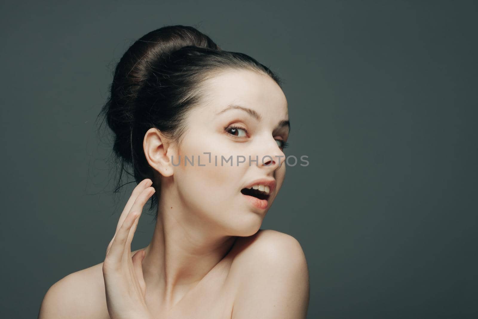 brunette with bare shoulders gathered hair hand near face. High quality photo