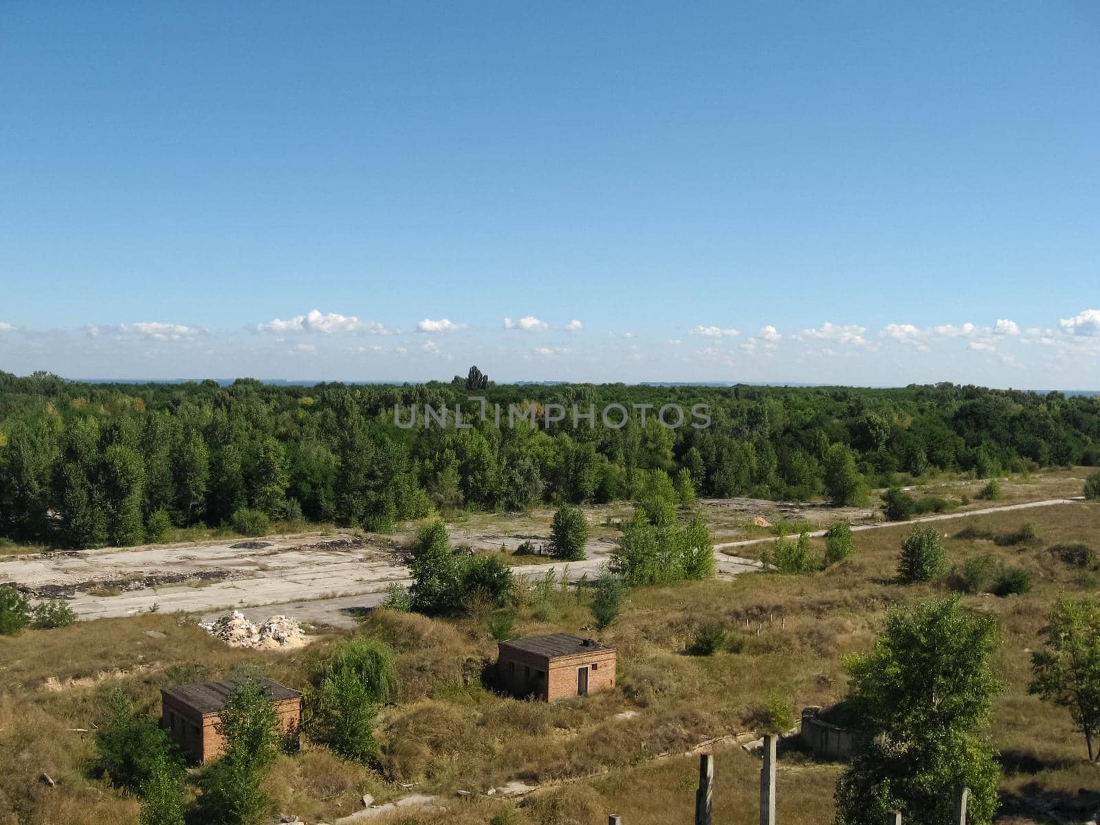 View from above on the site with old destroyed buildings, overgrown grass and trees.