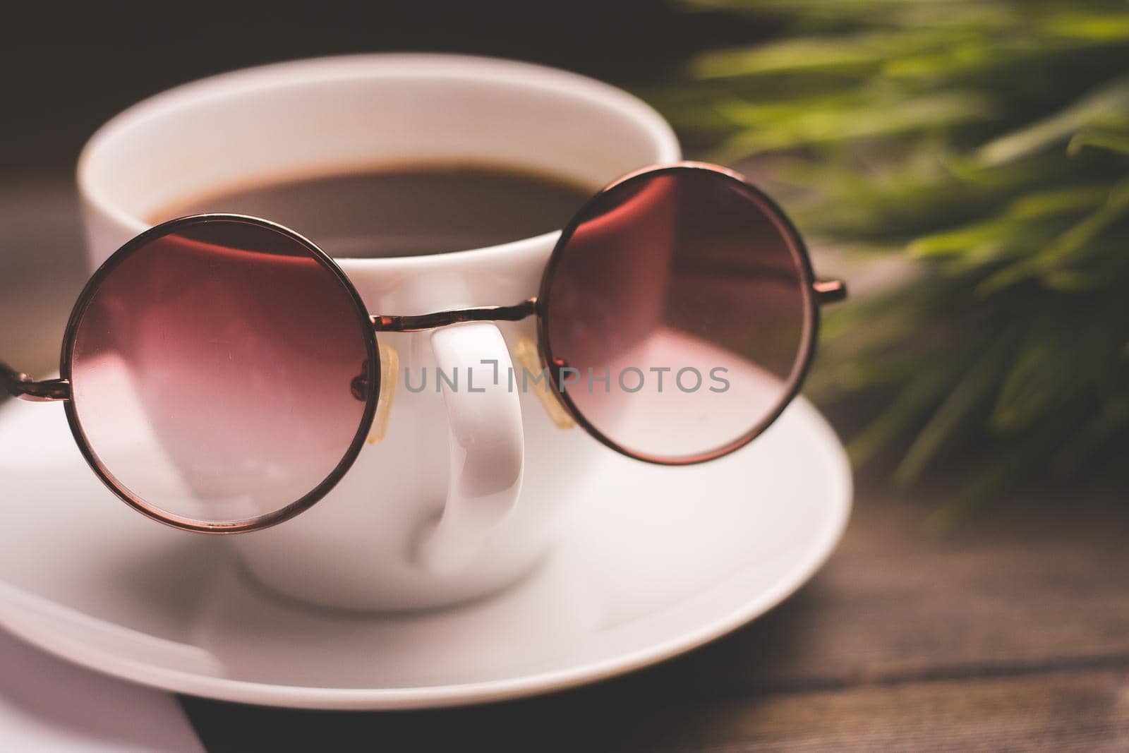 cup of coffee with glasses on a saucer and a wooden table flower in a pot in the background by SHOTPRIME