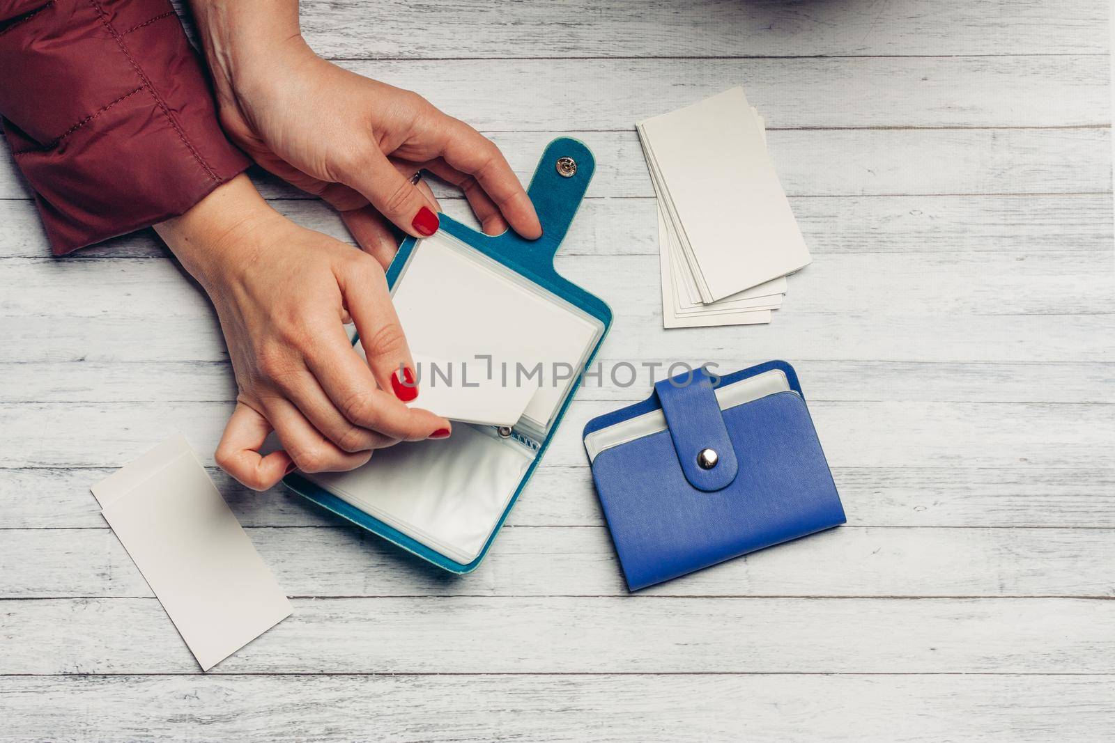 woman leafs through the sheets of business card holders on a wooden background finance sale by SHOTPRIME