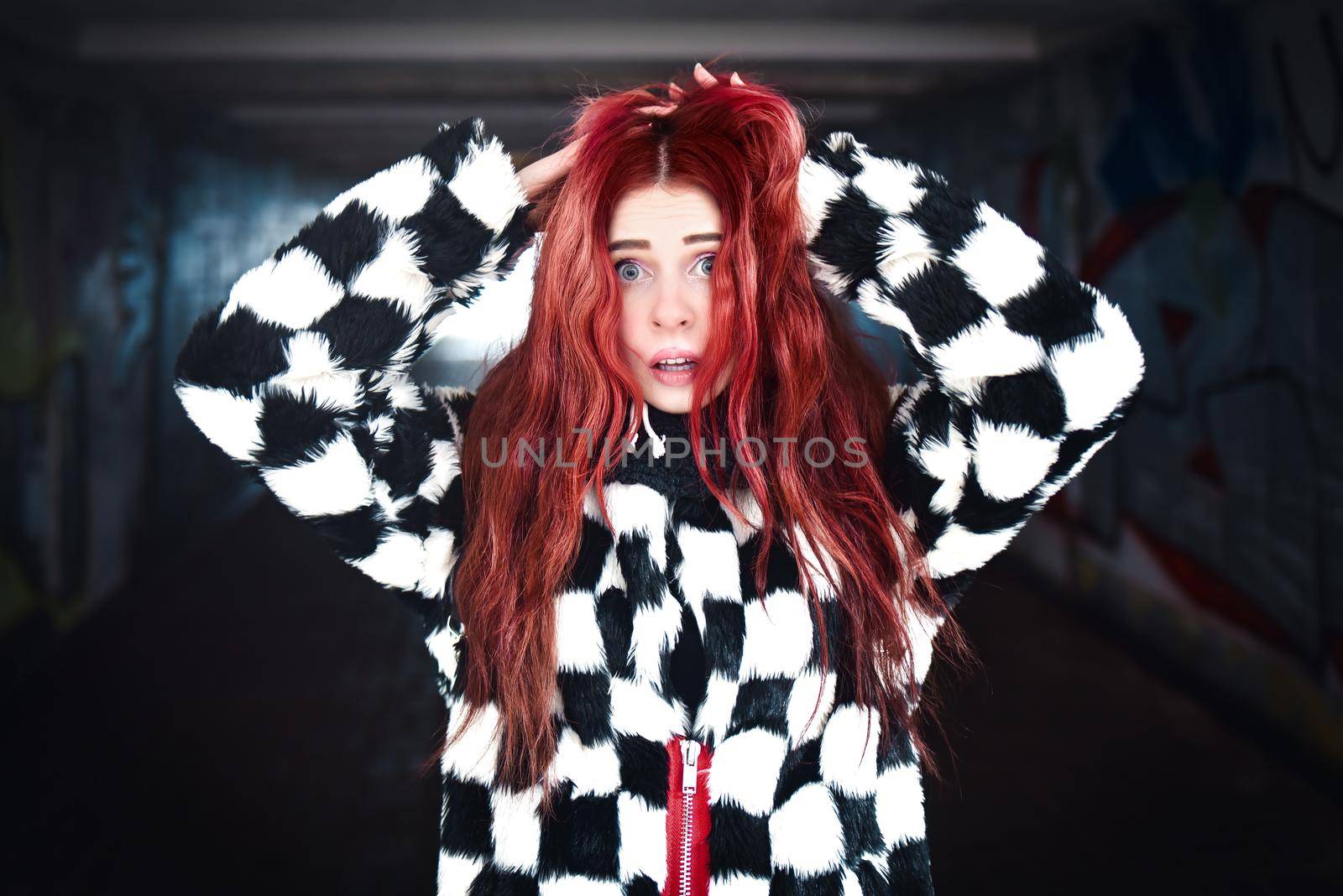 Concepts Against Violence. A very scared Girl with red hair stands near the exit of a dark subway. Expression emotion by Nickstock
