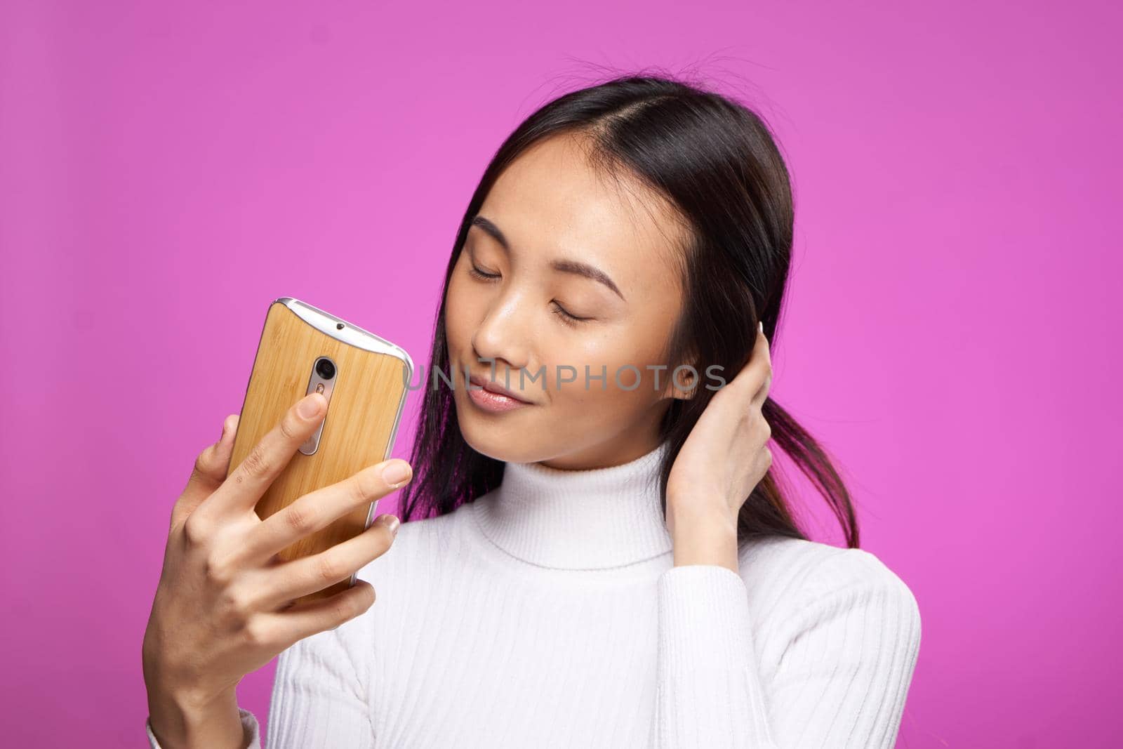 pretty woman asian appearance phone holding pink background cropped view. High quality photo