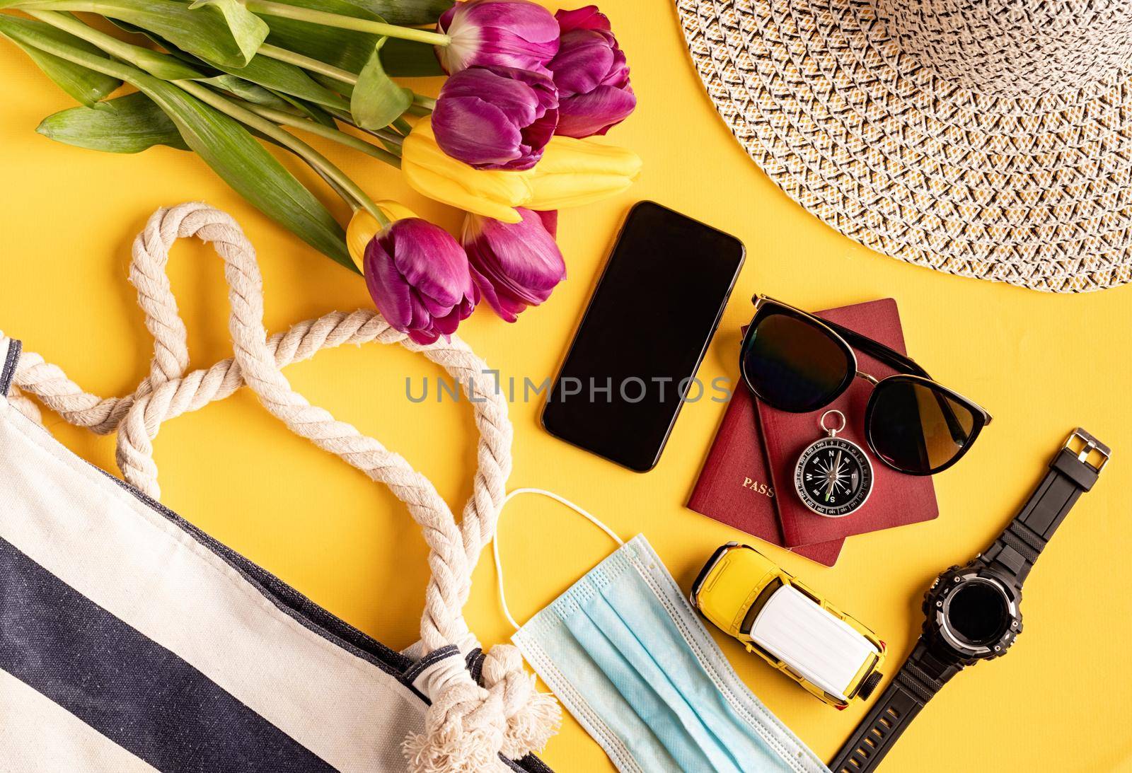 Flat lay travelling gear with passports, smartphone, sunglasses and compass on yellow background by Desperada