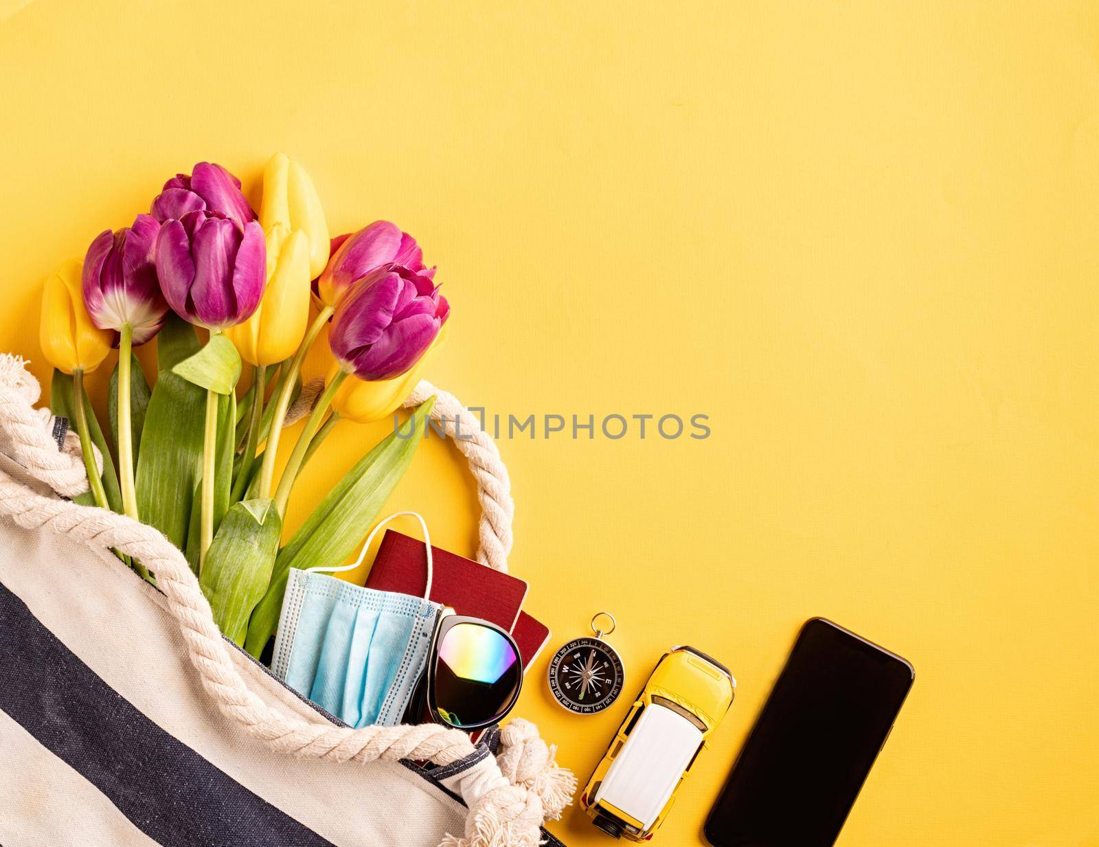 Flat lay travelling gear with passports, smartphone, sunglasses and compass on yellow background by Desperada