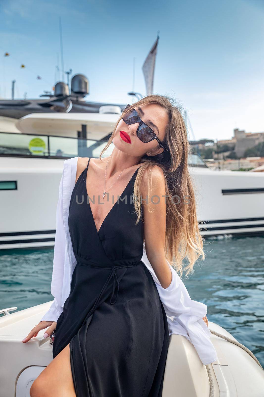 The elegant girl dressed in an evening dress of black color and sunglasses on the boat carry to the big yacht, gorgeous woman, sexual red lips, Decollete, Monaco, Monte-Carlo by vladimirdrozdin