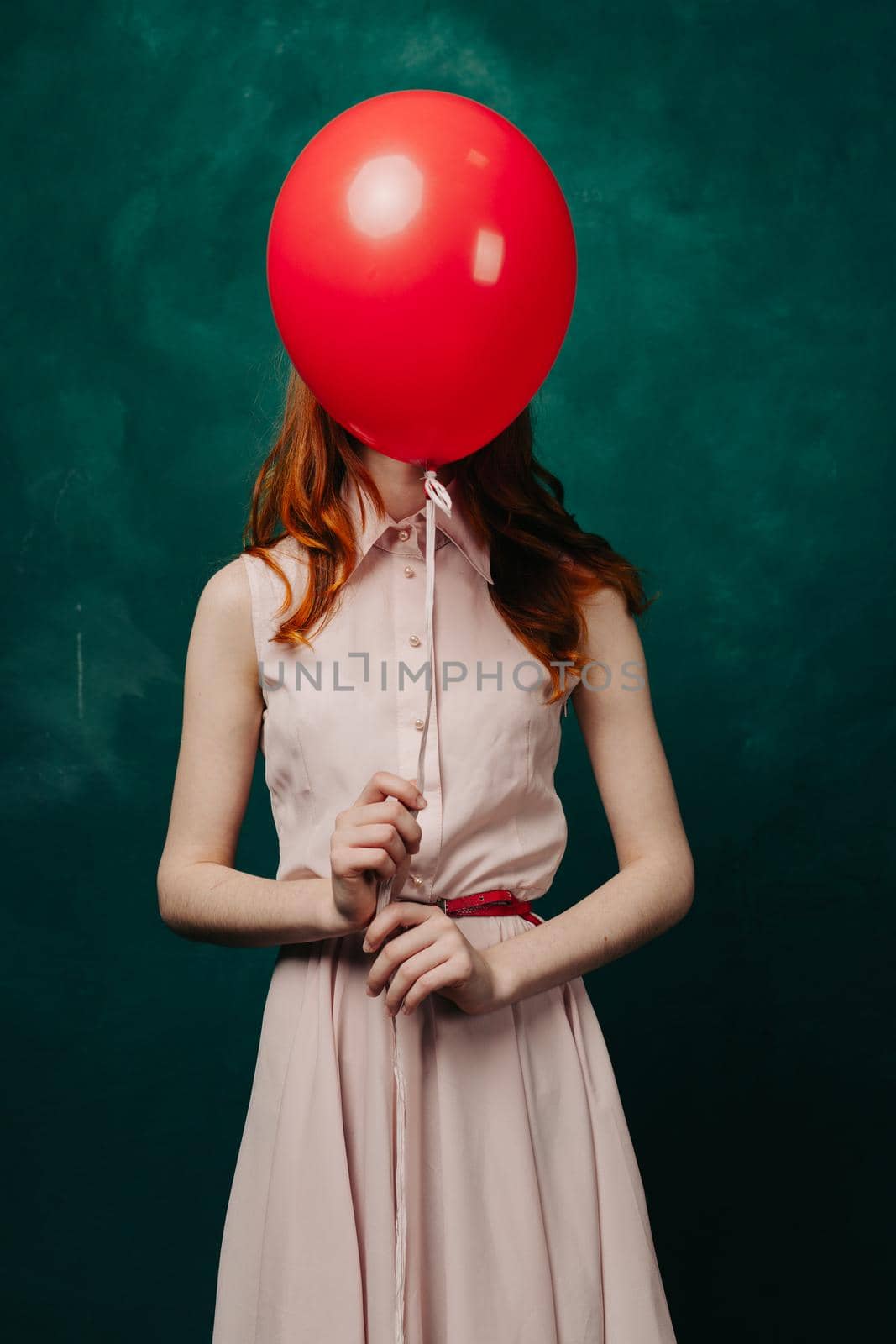 woman with a red balloon on a green background pink dress model. High quality photo