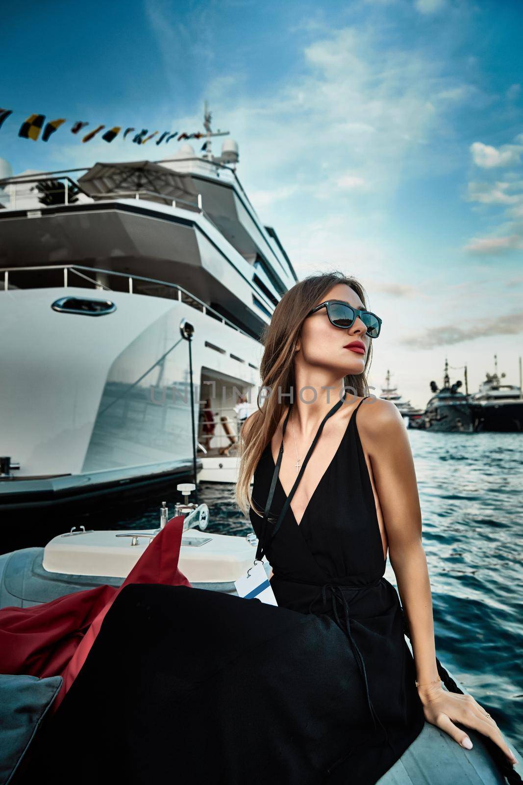 Monaco, Monte-Carlo, 27 September 2019: A glamorous girl in an evening dress of black color and sunglasses on the boat carry to the big yacht, Monaco