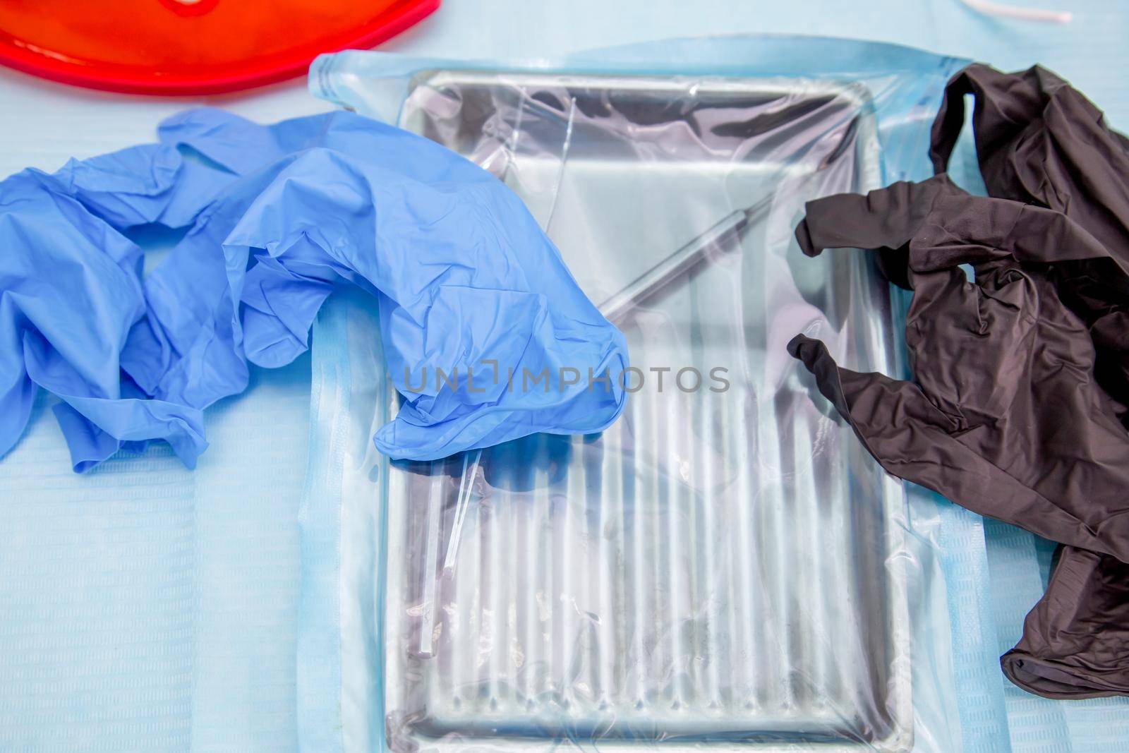 Sterile medical instruments in packaging and blue and black disposable gloves in a medical office. Surgical and dentistry equipment on the table.