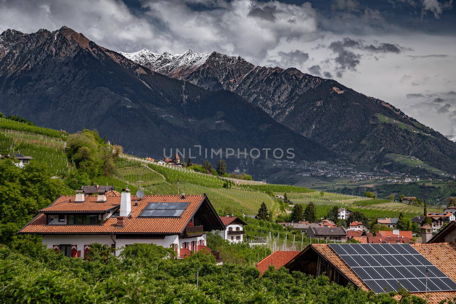 Panorama of solar batteries on roof top, green slopes of the mountains of Italy, Trentino, Dolomites, huge clouds over a valley, green meadows, a clear energy, energy of the sun, Solar panels by vladimirdrozdin