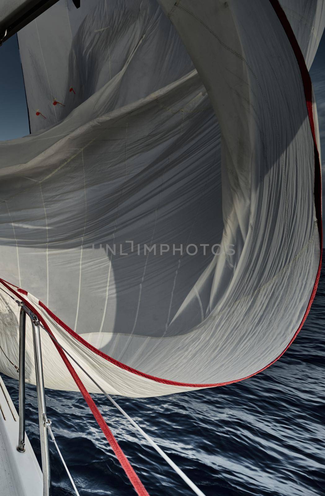 Spinnaker of white color, the sail flutters on a wind, sailing regatta at sunset, a race, reflection on water by vladimirdrozdin