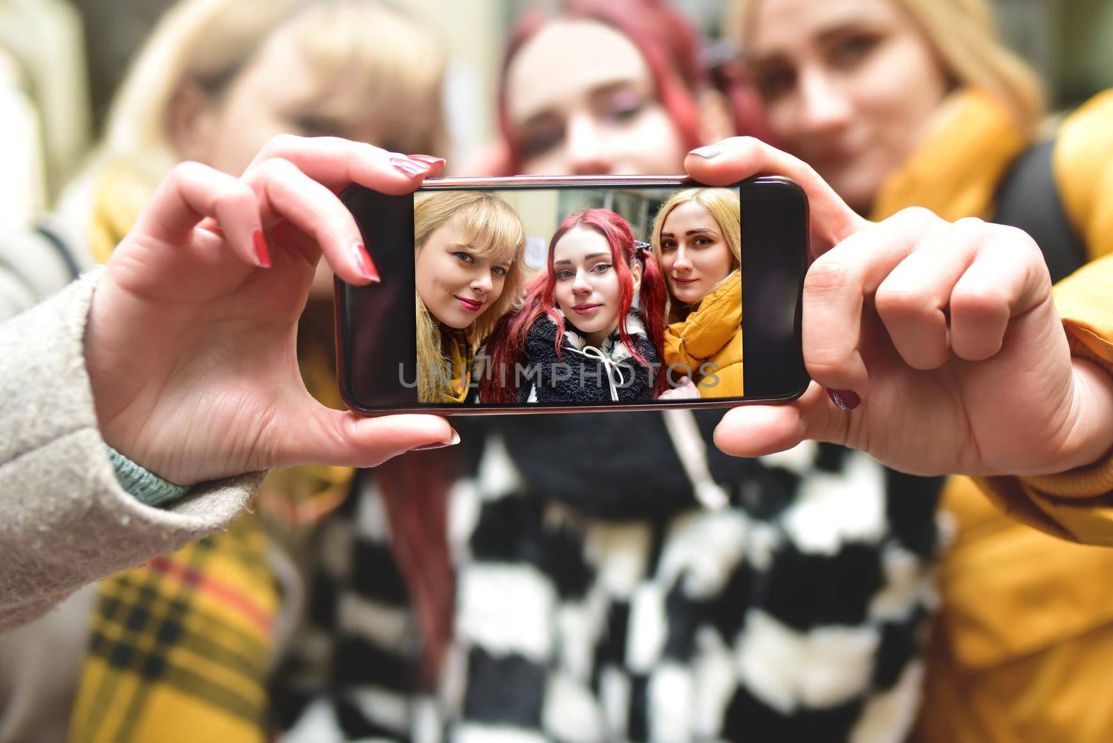 Three beautiful girlfriends in good spirits take a selfie in town. friendship concept by Nickstock