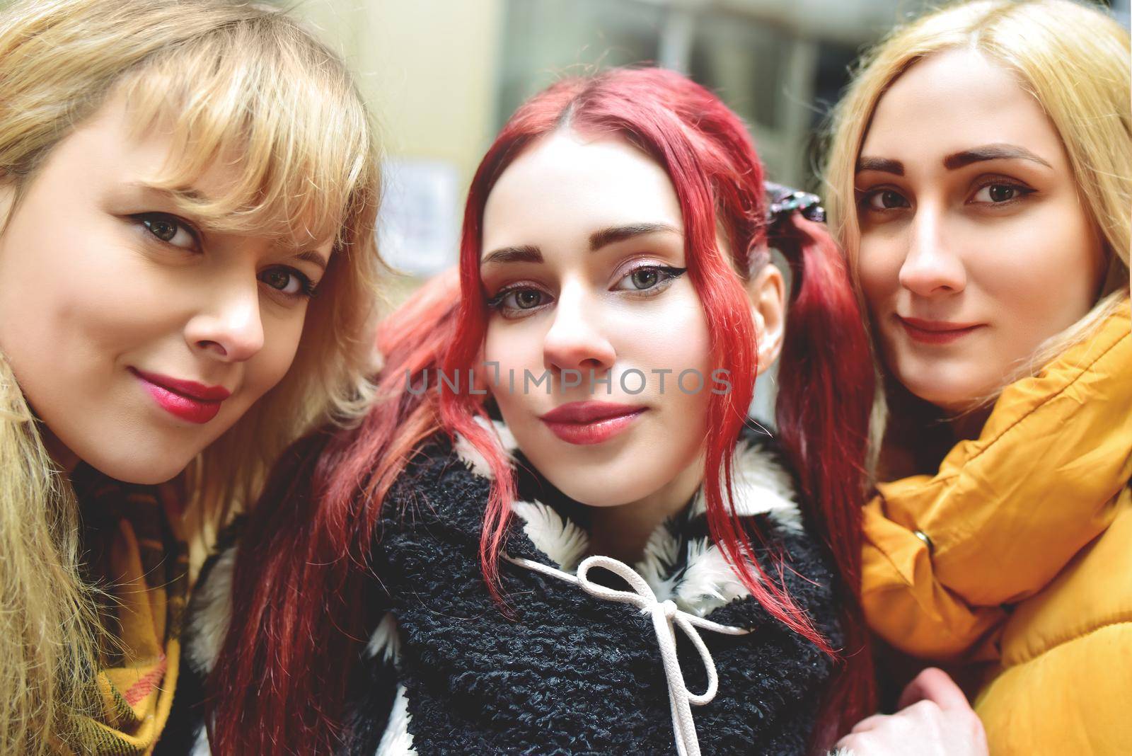 Three beautiful girlfriends in good spirits take a selfie in town. The concept of friendship