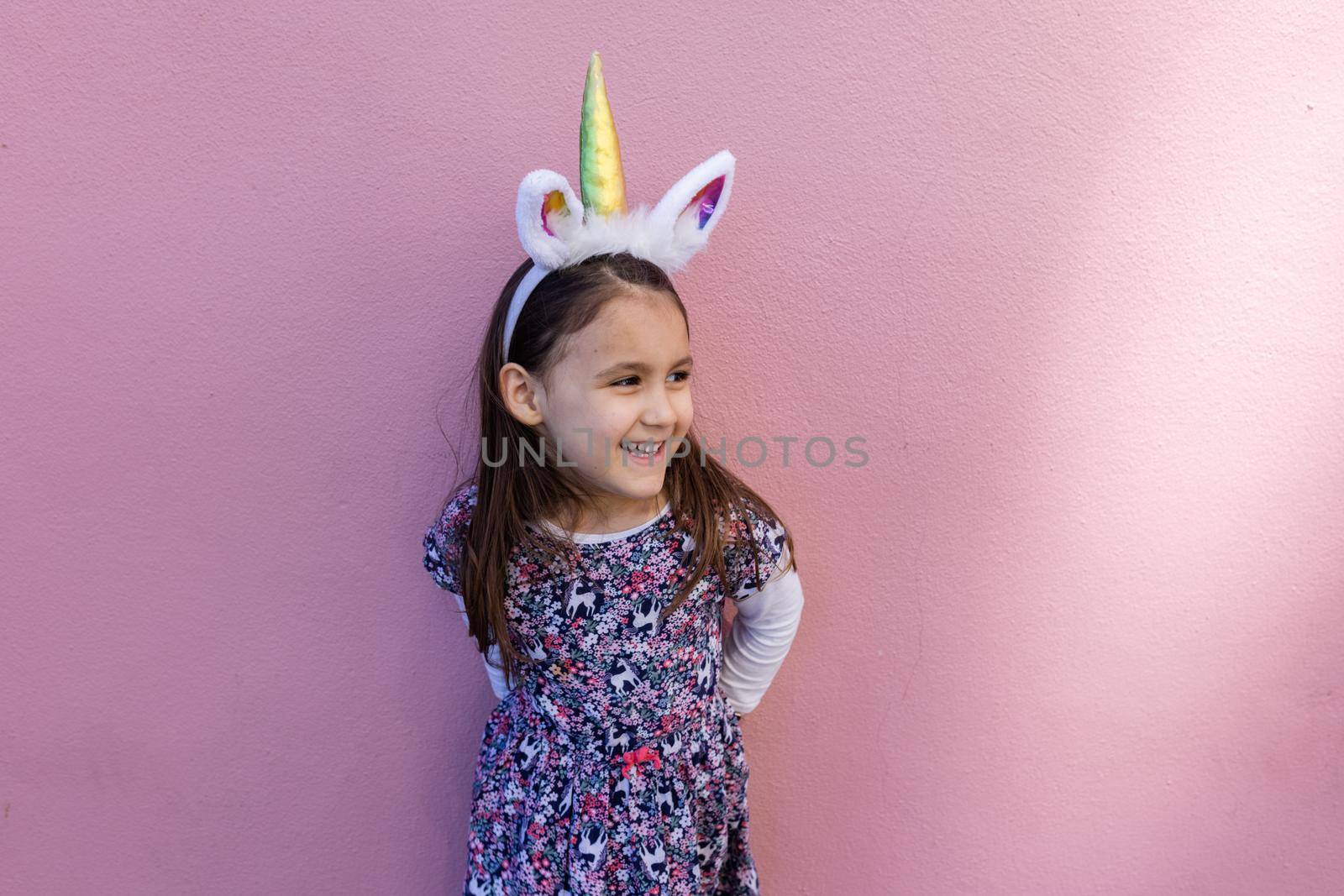 Adorable little girl wearing a unicorn headband with pink background by Kanelbulle