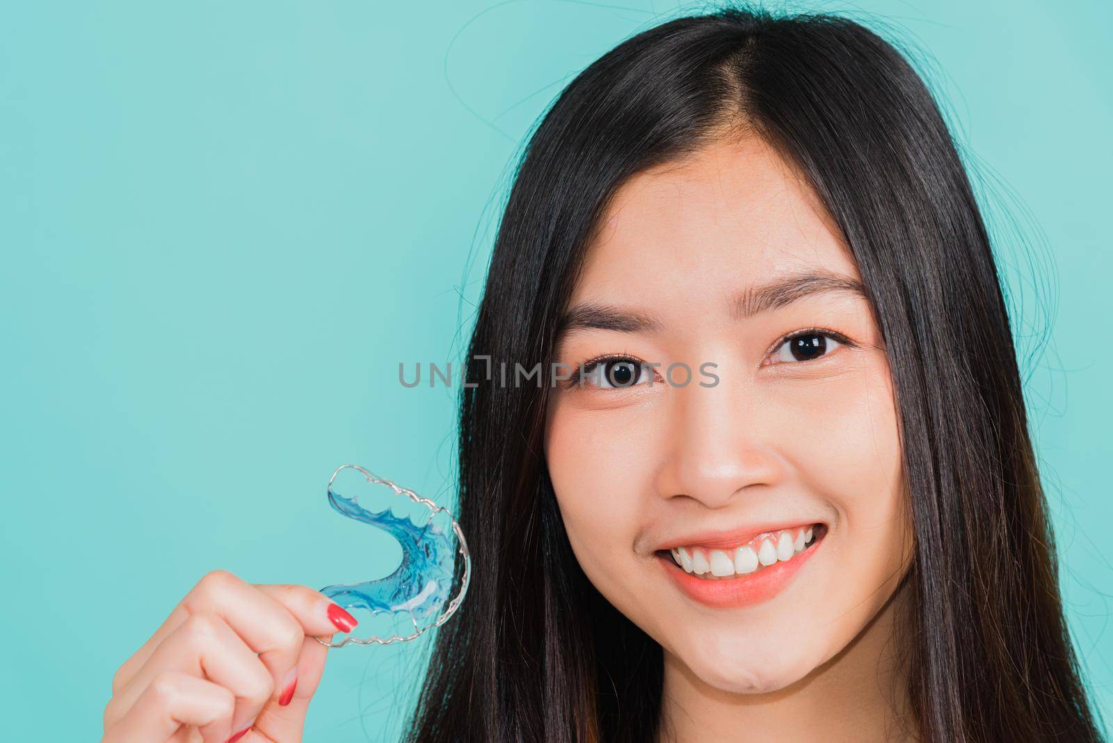 woman smiling holding silicone orthodontic retainers for teeth by Sorapop