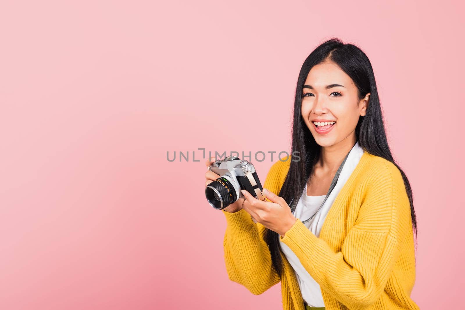 Attractive energetic happy Asian portrait beautiful cute young woman teen excited smiling holding vintage photo camera, studio shot isolated on pink background, traveler female photographer