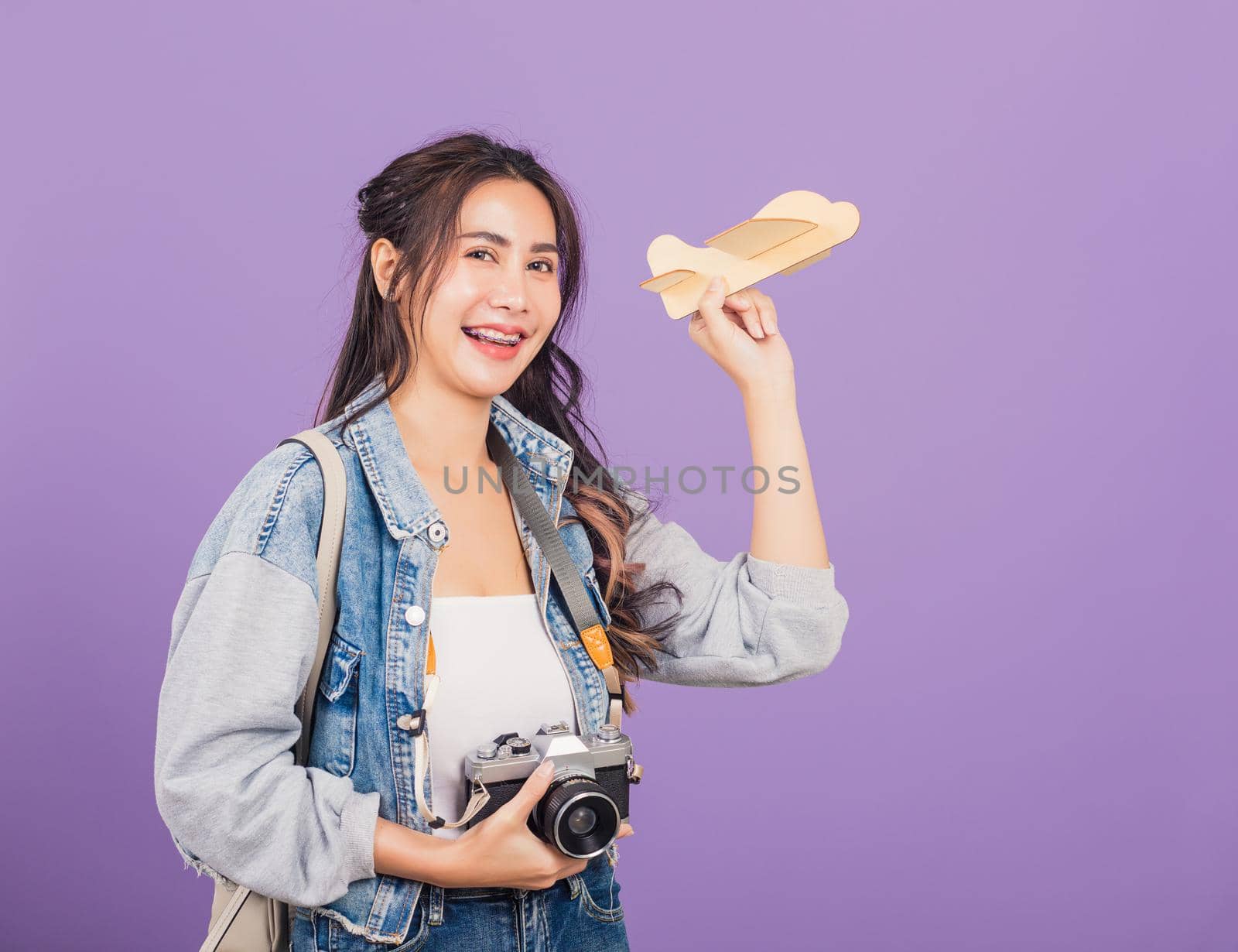 woman excited smiling holding airplane toy and retro vintage photo camera by Sorapop