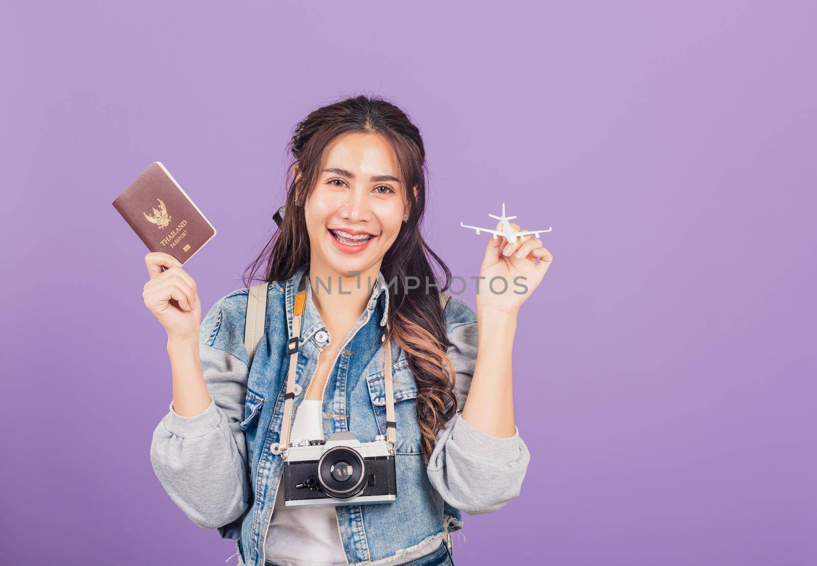 woman excited smiling in summer vacation holding airplane toy, passport and vintage photo camera by Sorapop