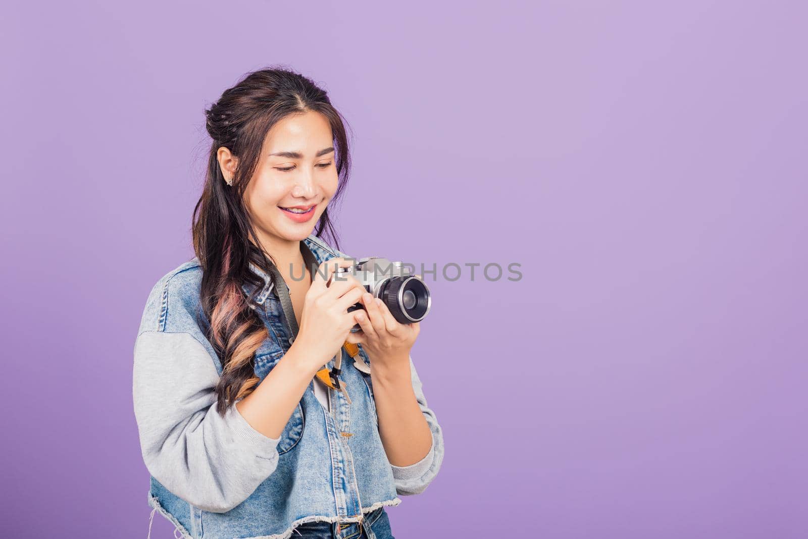 young woman smiling excited wear denims holding vintage photo camera by Sorapop