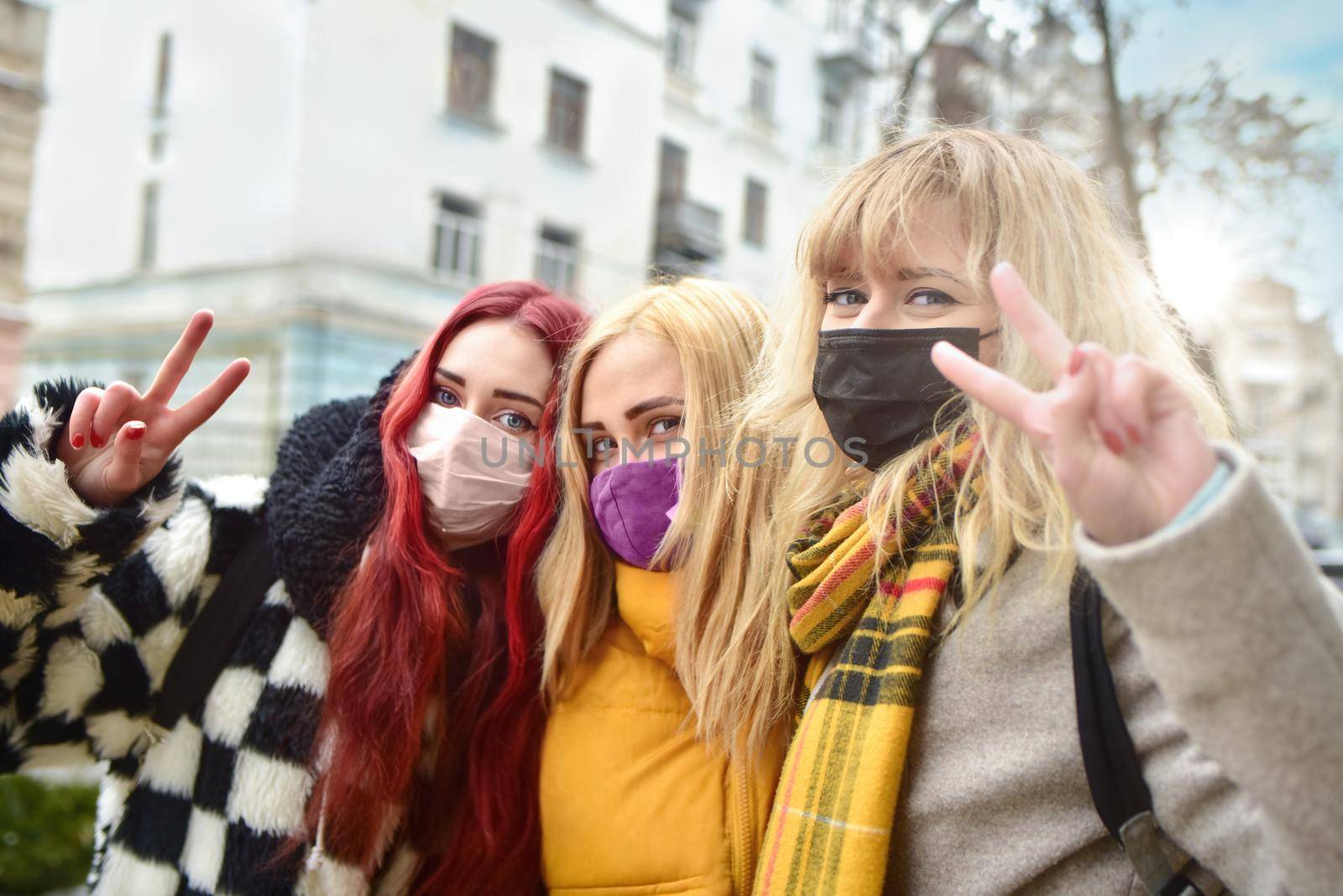 portrait of a group of girls with protected wearing masks, making the Two Finger Peace Sign Hand Gesture . Concept of happiness and security at the quarantine time