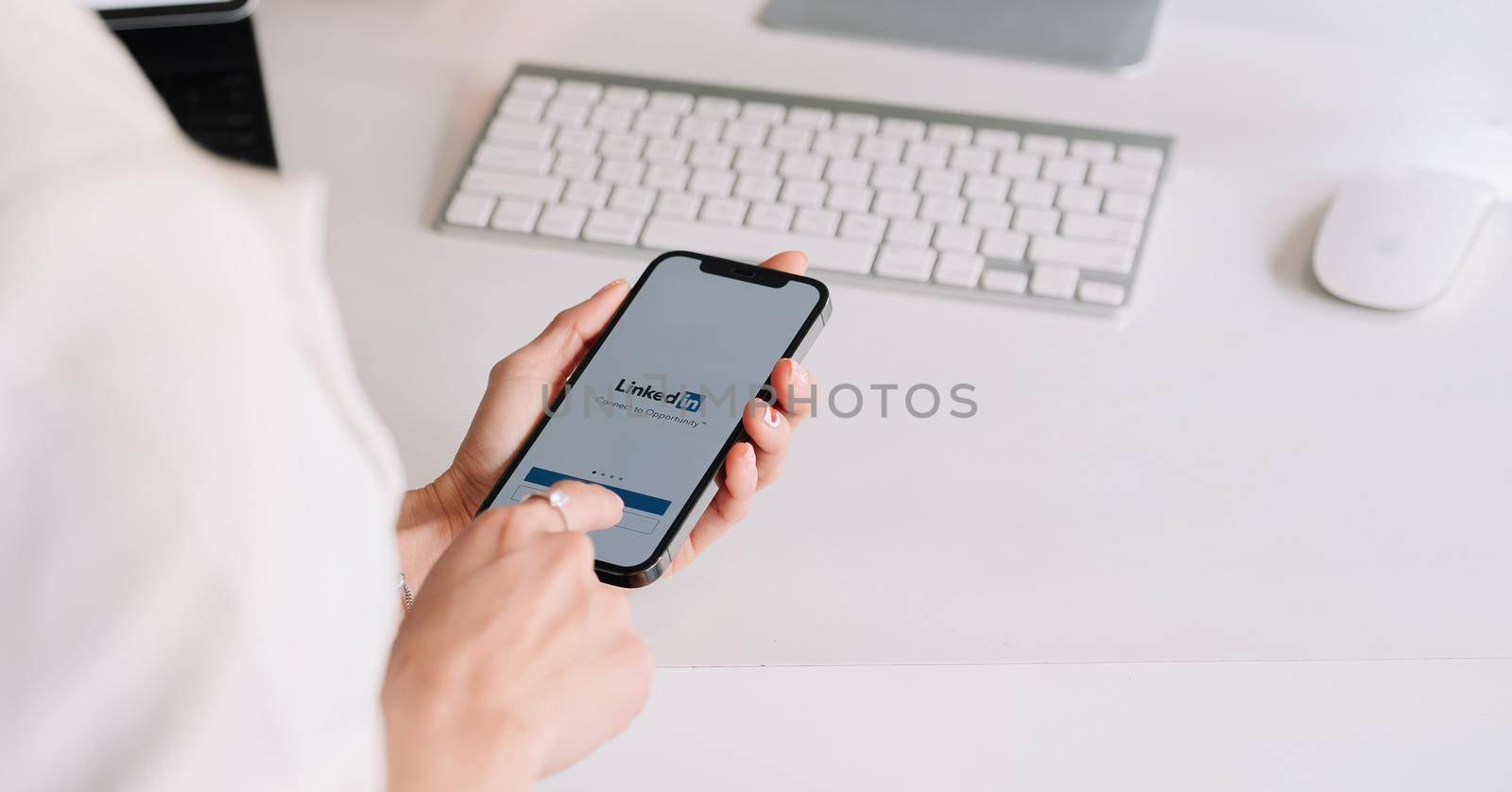 CHIANG MAI ,THAILAND MAR 13, 2019 : A woman holding a iPhone 12 with social network service LinkedIn on the screen. iPhone 12 was created and developed by the Apple inc.