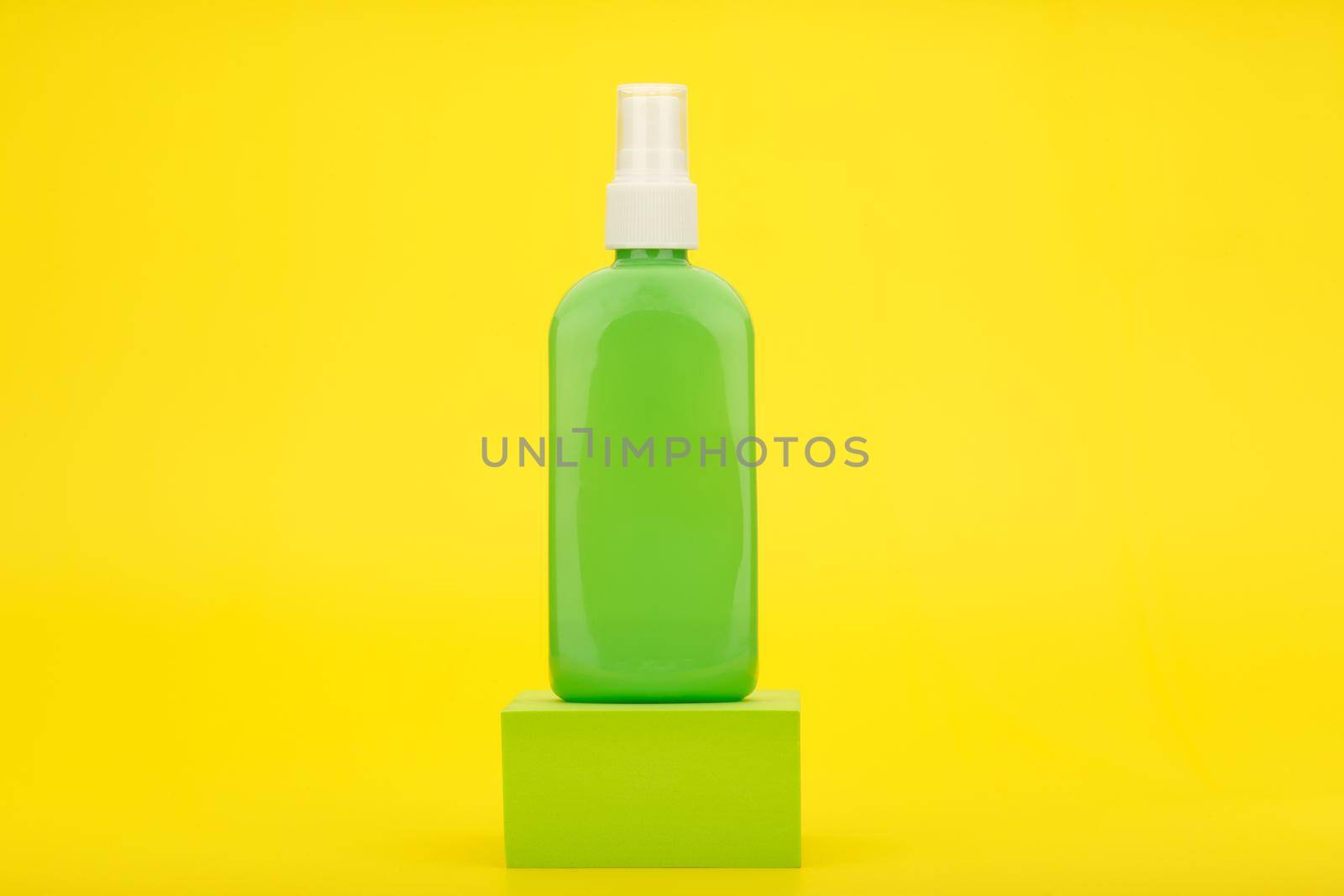 Spray for sun protection with sunscreen in green tube on podium against yellow background with copy space.  by Senorina_Irina