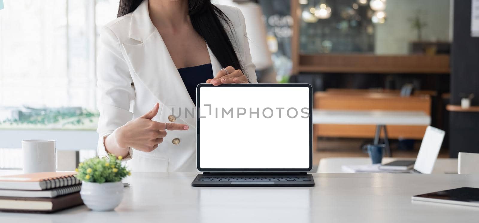 Businesswoman shows the laptop with blank screen in a front view shot