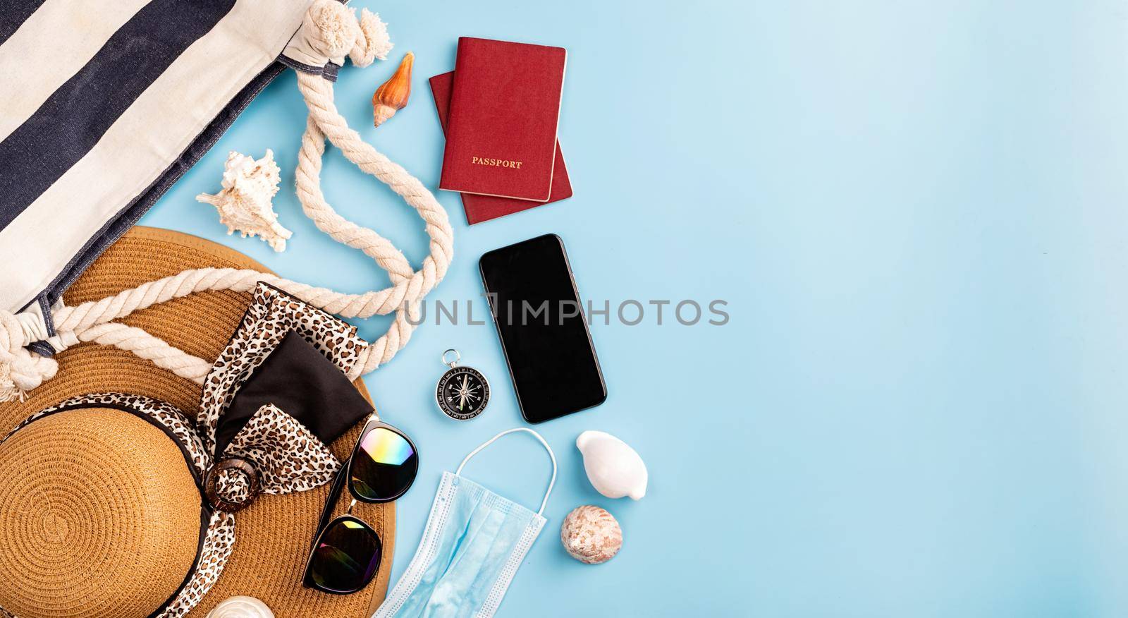 Travel and adventure.Flat lay travelling objects with summer hat, smartphone, passport, sunglasses and compass on blue background with copy space