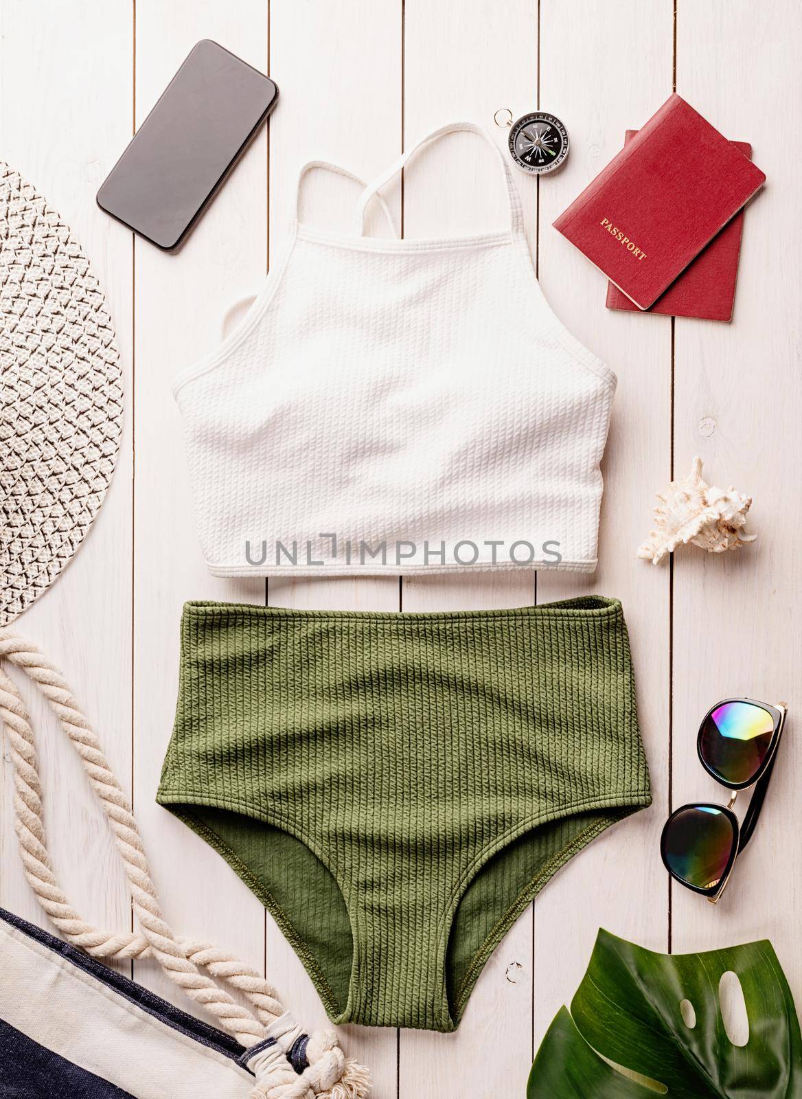 Flat lay travelling objects with swimsuit, smartphone, passports, sunglasses and compass on white wooden background by Desperada