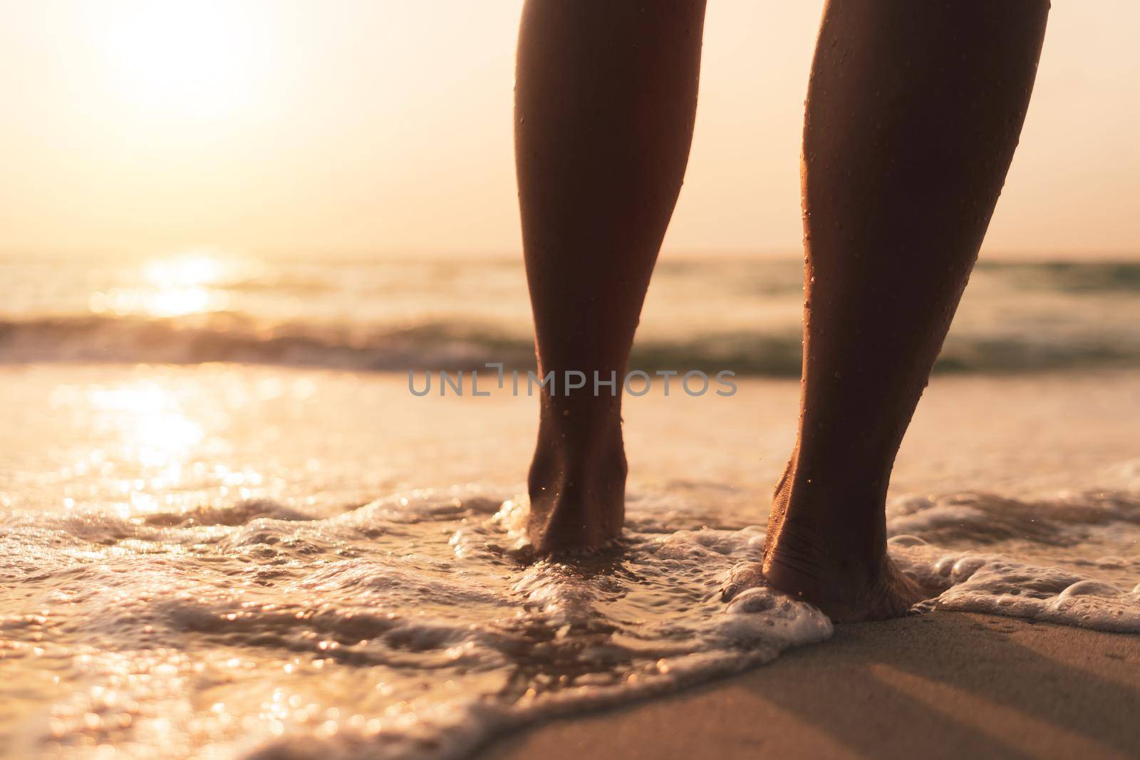 Woman feet walk slow life and relax on sand tropical beach with sunset sunrise sky background.