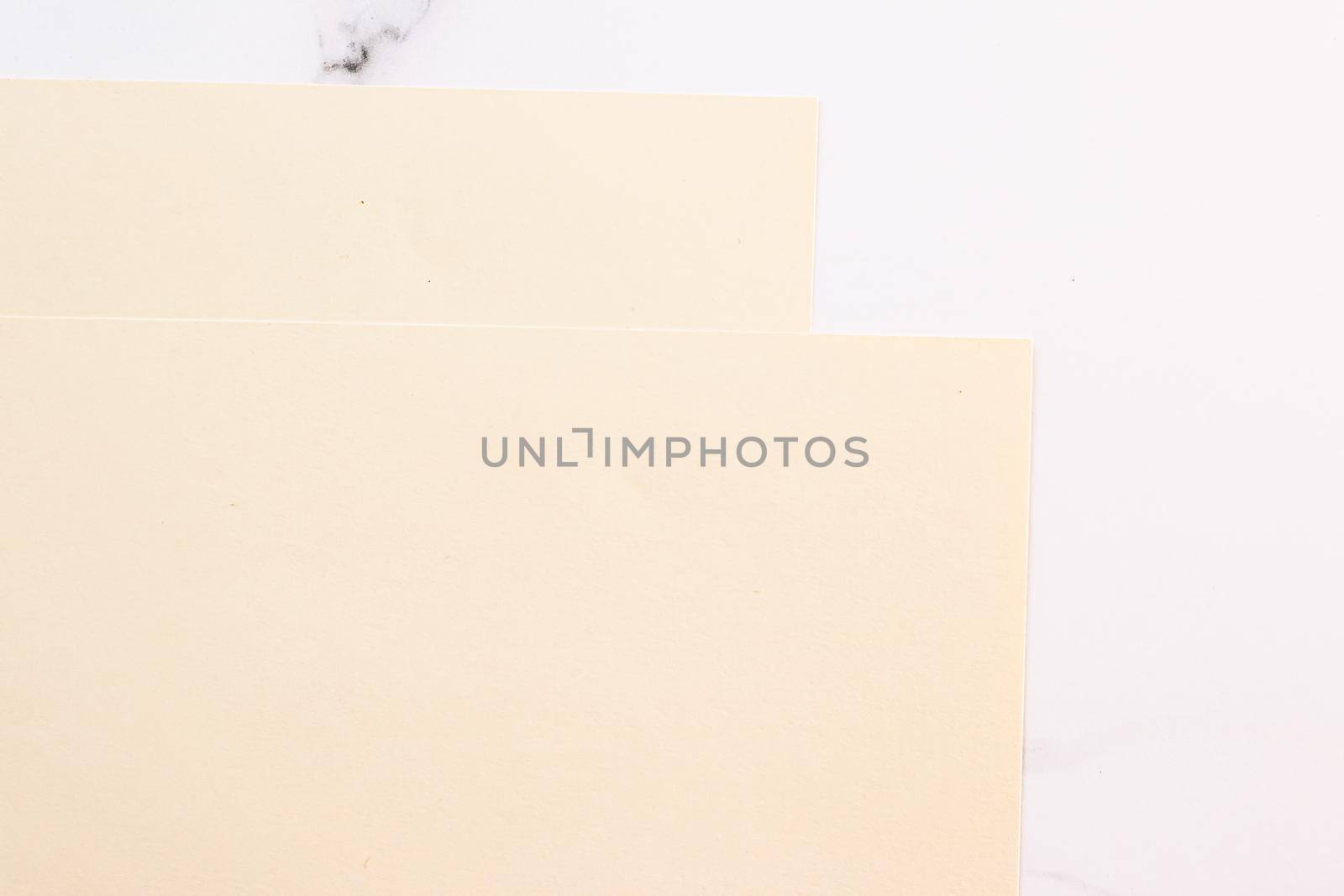 Beige A4 papers on white marble background as office stationery flatlay, luxury branding flat lay and brand identity design for mockups