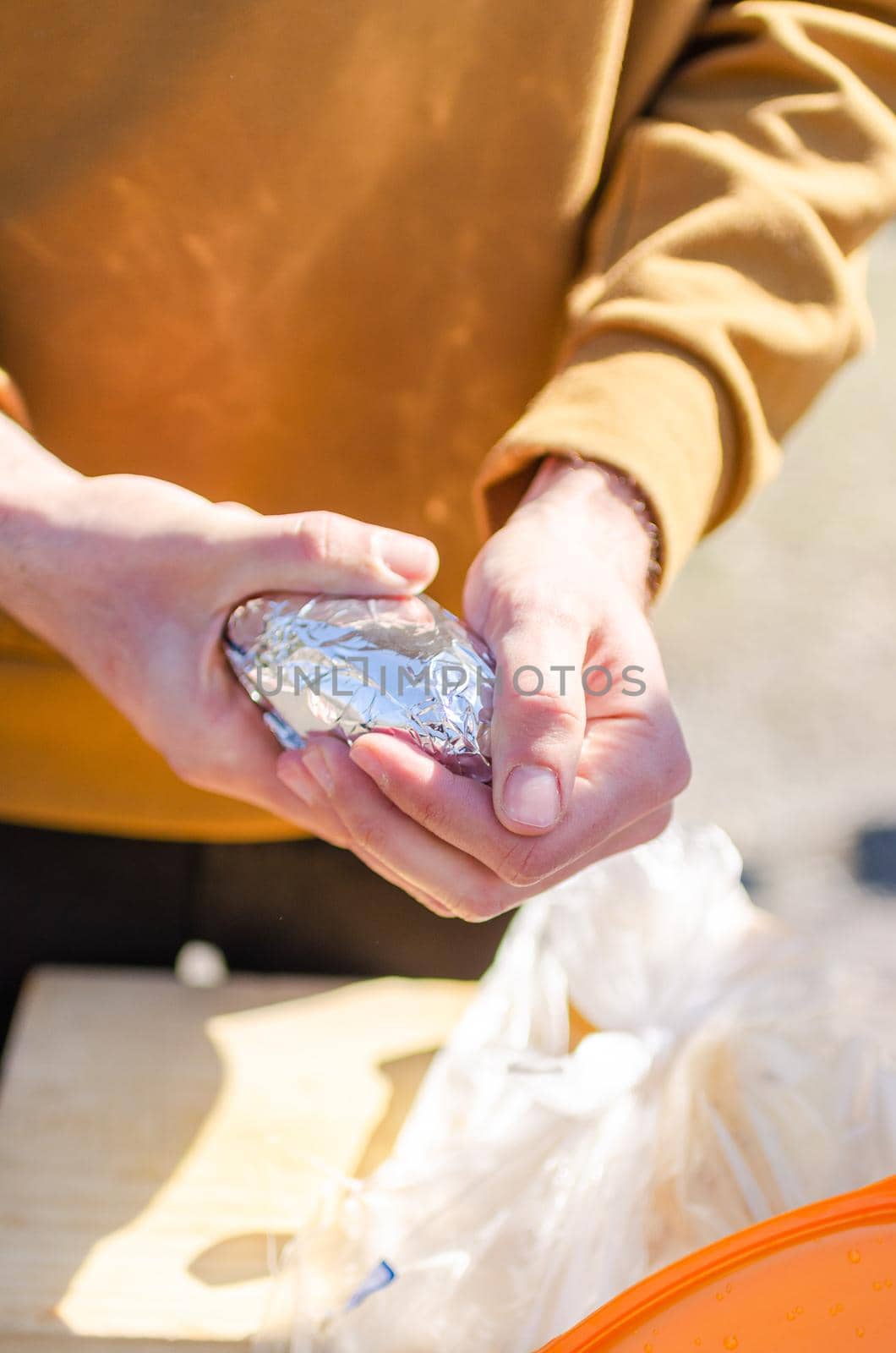Young man with potatoes in his hands on a sunny day,