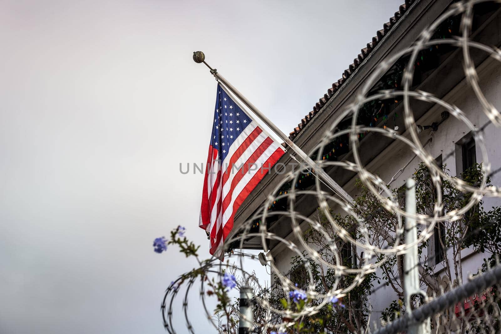 Concept of political isolationism and economic slowdown in the United States of America. Flag behind barbed wire.