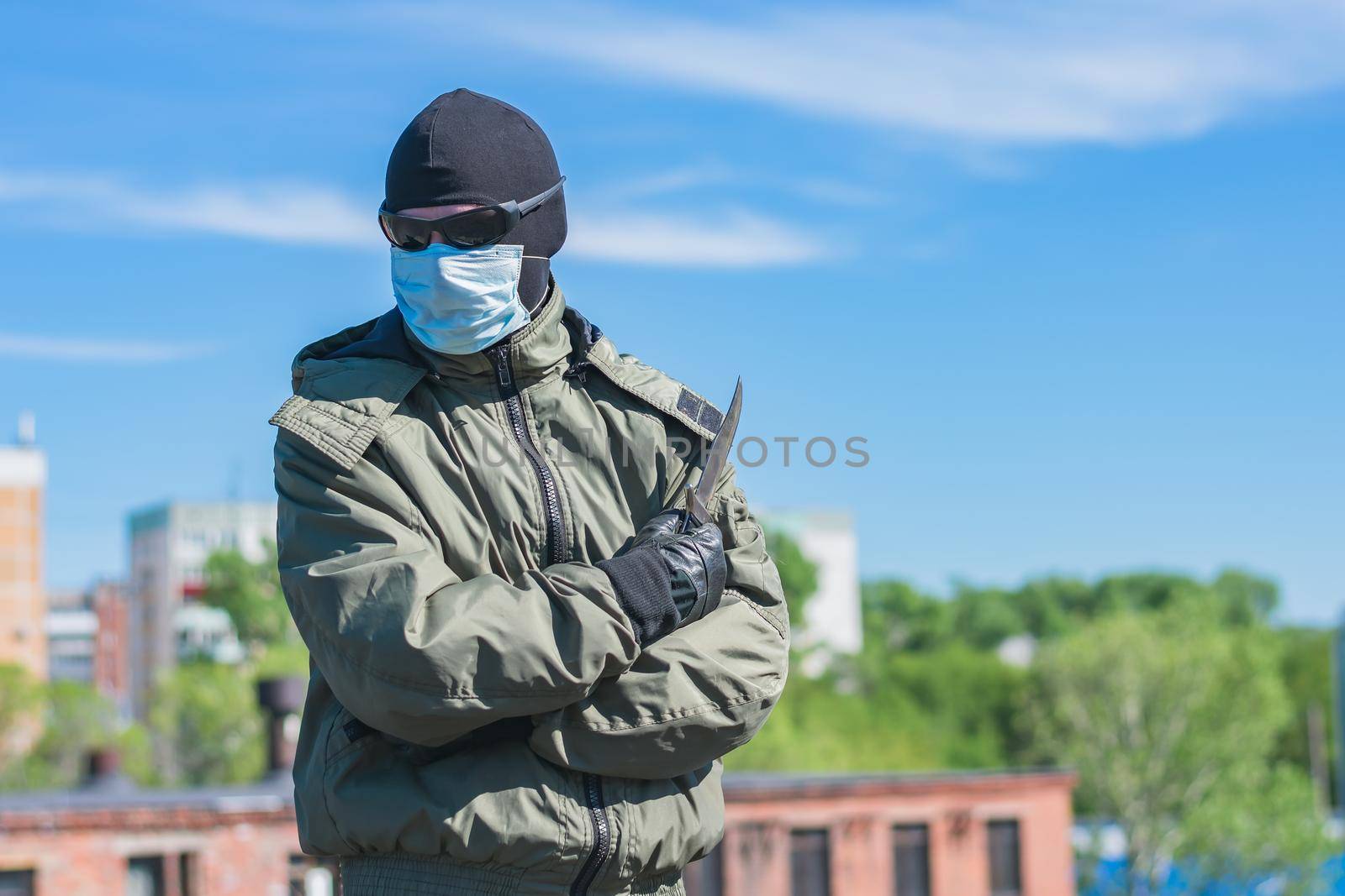 An intruder in a mask and with a weapon stands on the street