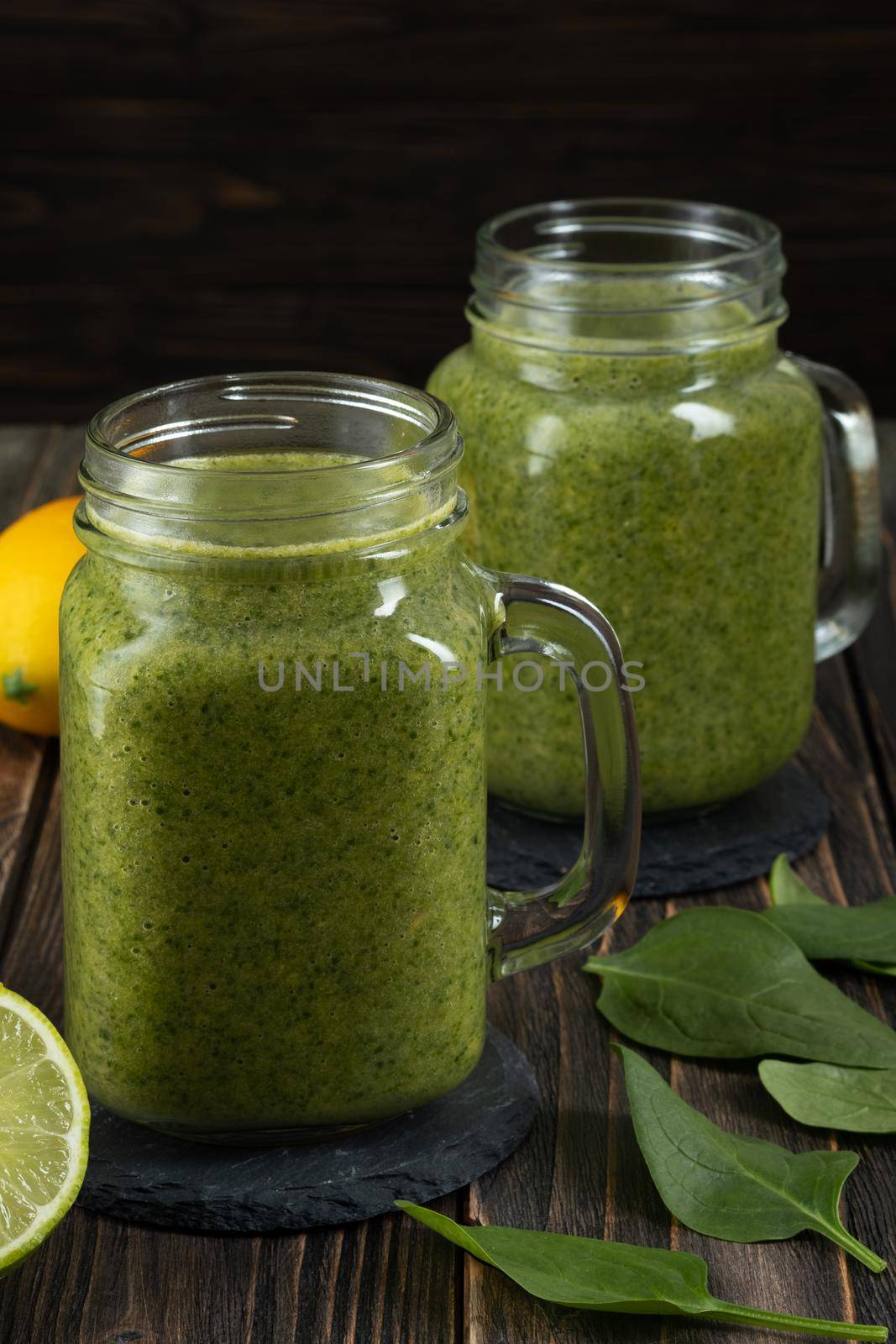 Healthy green smoothie with spinach, mango, orange,lime, apple,citrone in glass jars.