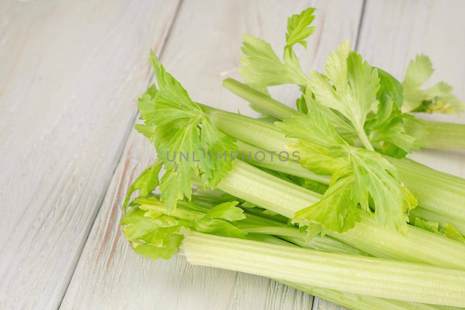 Bunch of fresh celery stalk with leaves on a wooden background by Fischeron