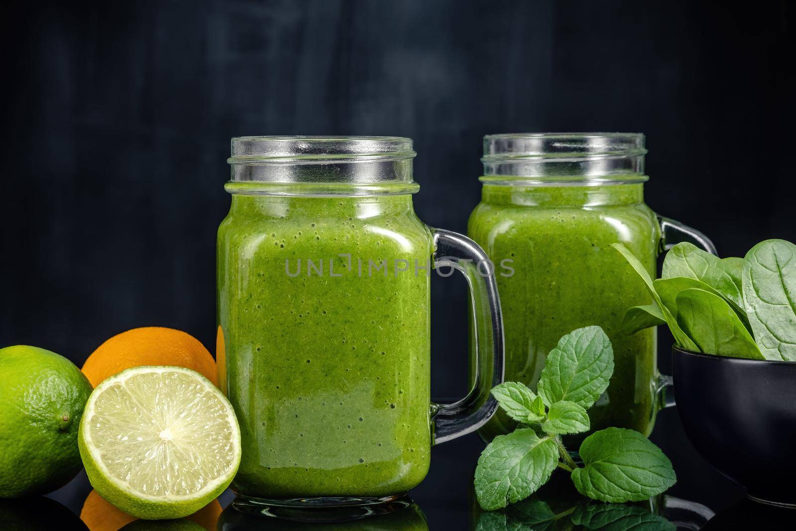 Healthy green smoothie with spinach, mango, orange,lime, apple,citrone in glass jars.