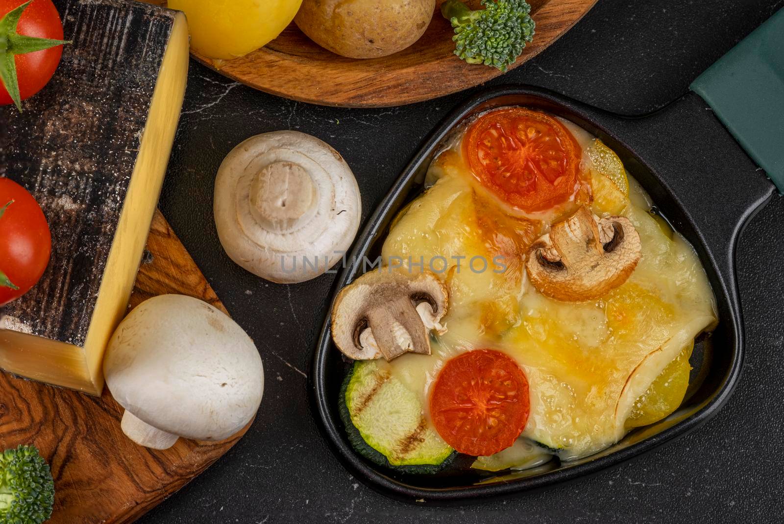 Delicious traditional Swiss melted raclette cheese on chopped boiled potatoes  by Fischeron