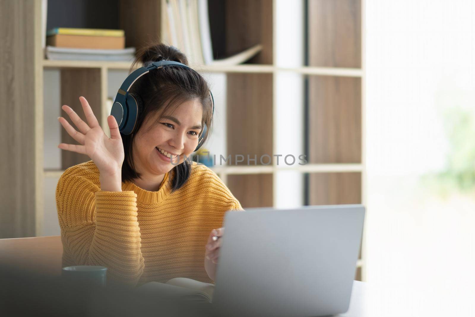Video call communication lead asian leader talk to colleagues work from home office wear headphones at virtual meeting. Student use laptop and internet e-learning remotely. by nateemee