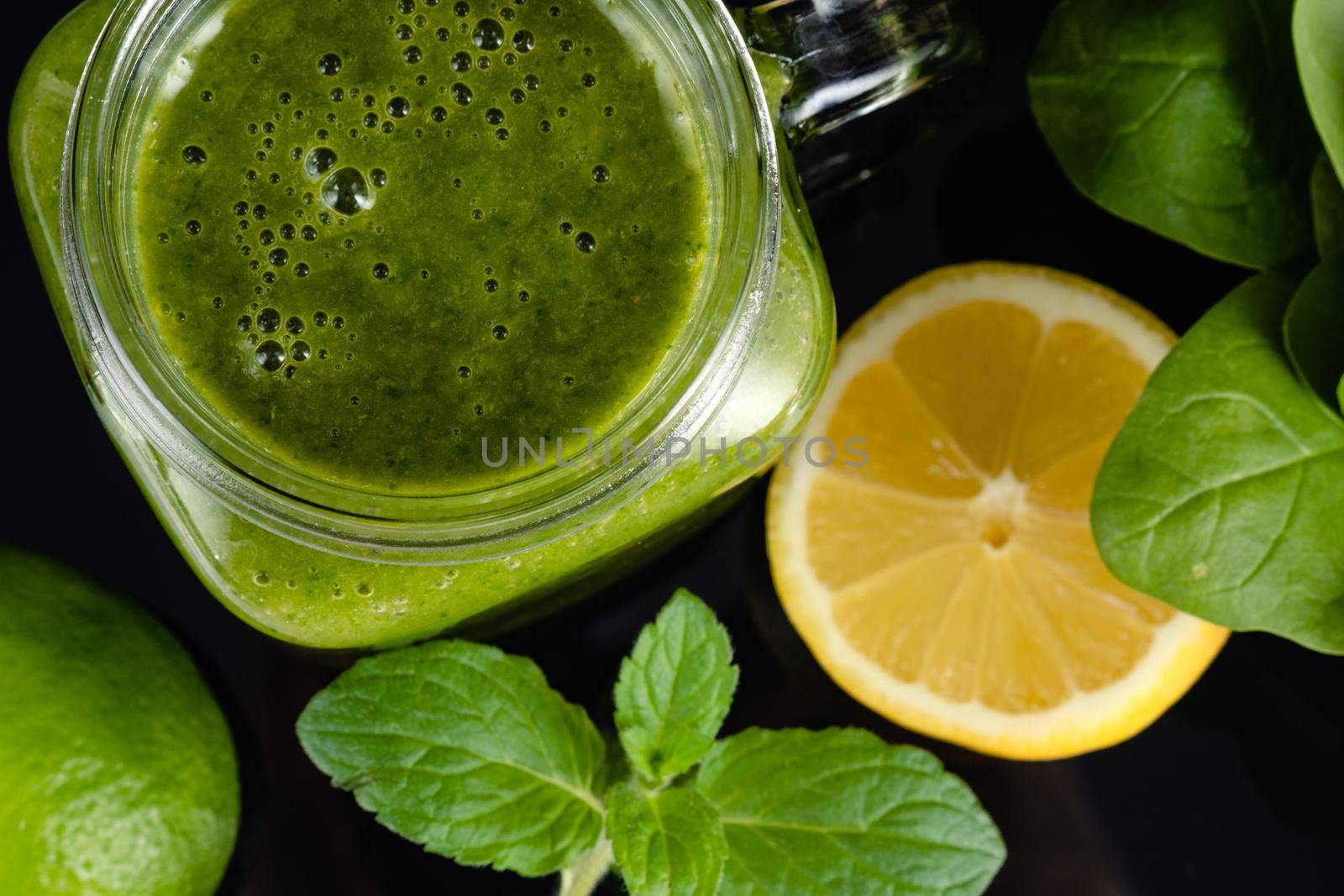 Healthy green smoothie with spinach, mango, orange,lime, apple,citrone in glass jars.