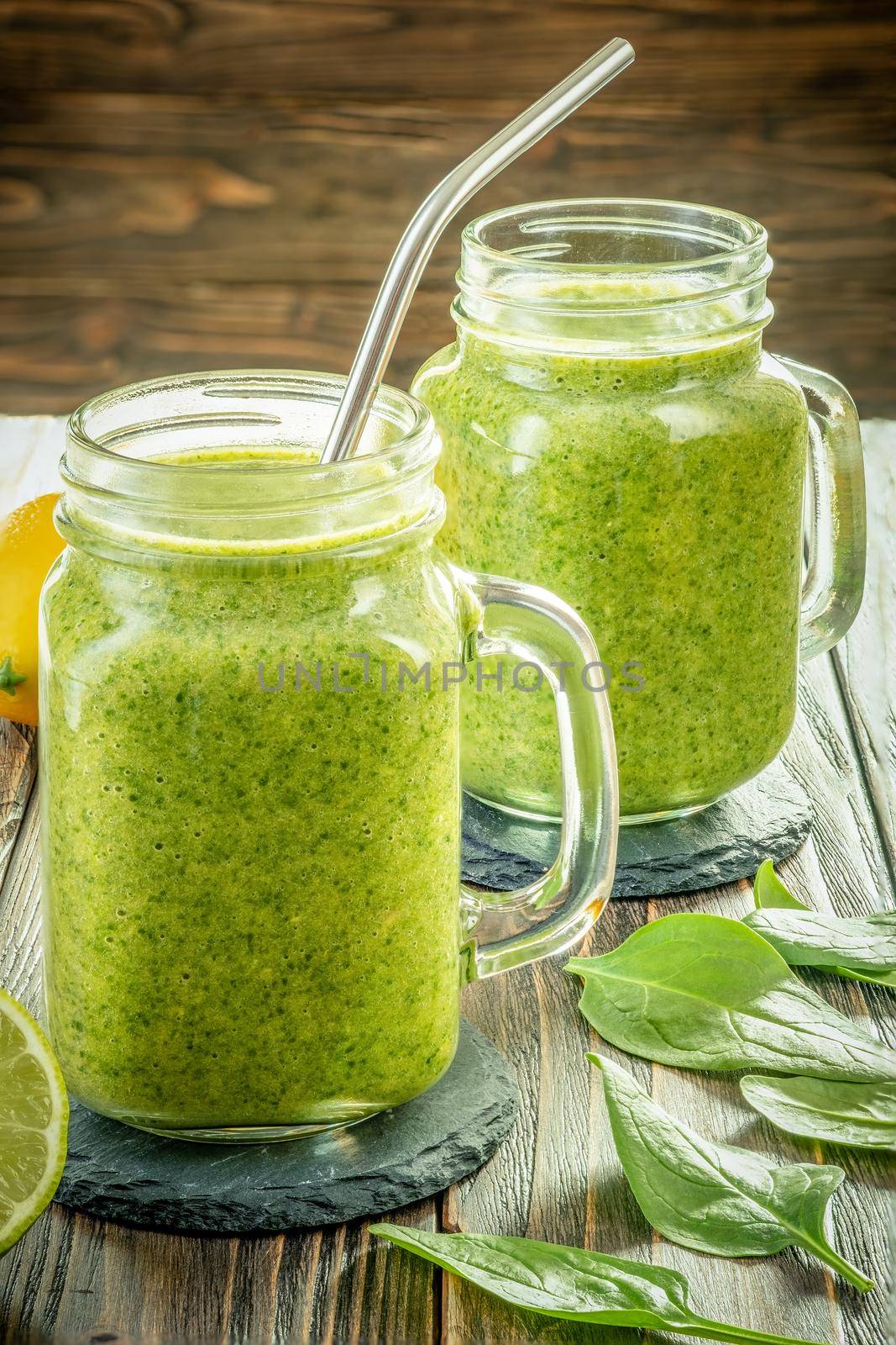 Healthy green smoothie with spinach, mango, orange,lime, apple,citrone in glass jars.