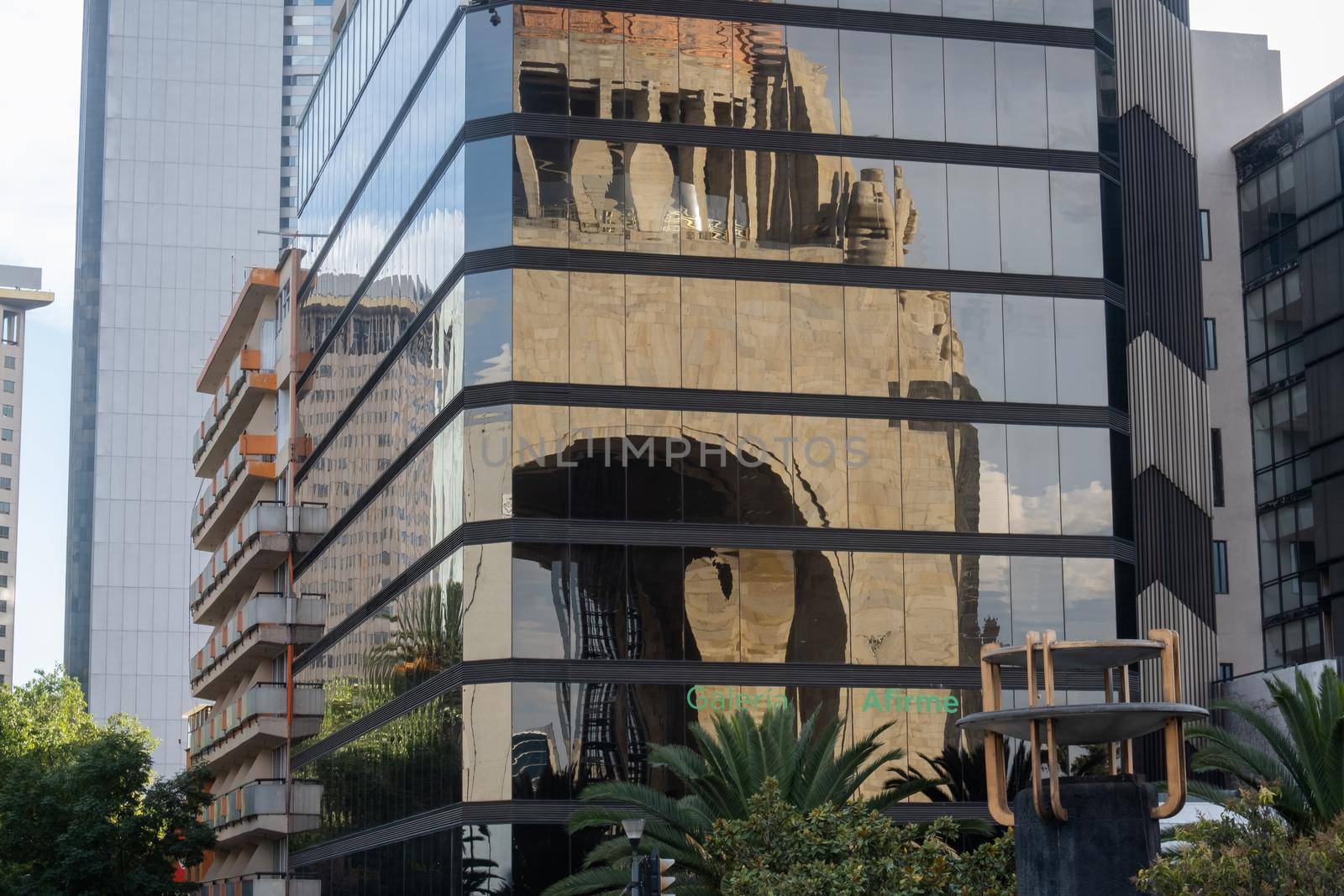 Reflection of the Monument to the Revolution on the windows of tall and modern building. Mirror-like building reflecting triumphal arch from Mexico City. Mexican landmarks